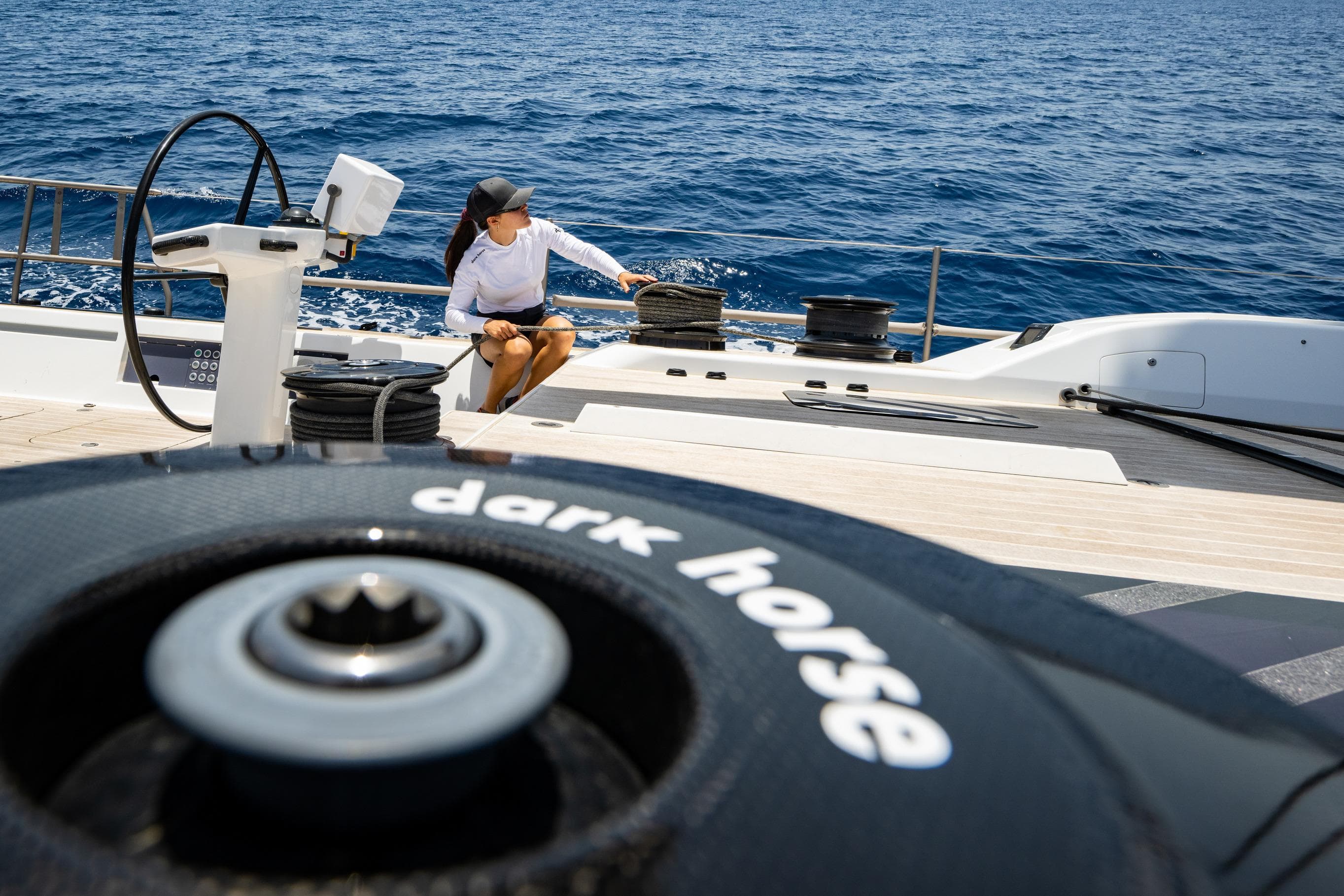 Person on Nautor Swan 80 FD yacht deck, ocean view, "dark horse" winch visible.