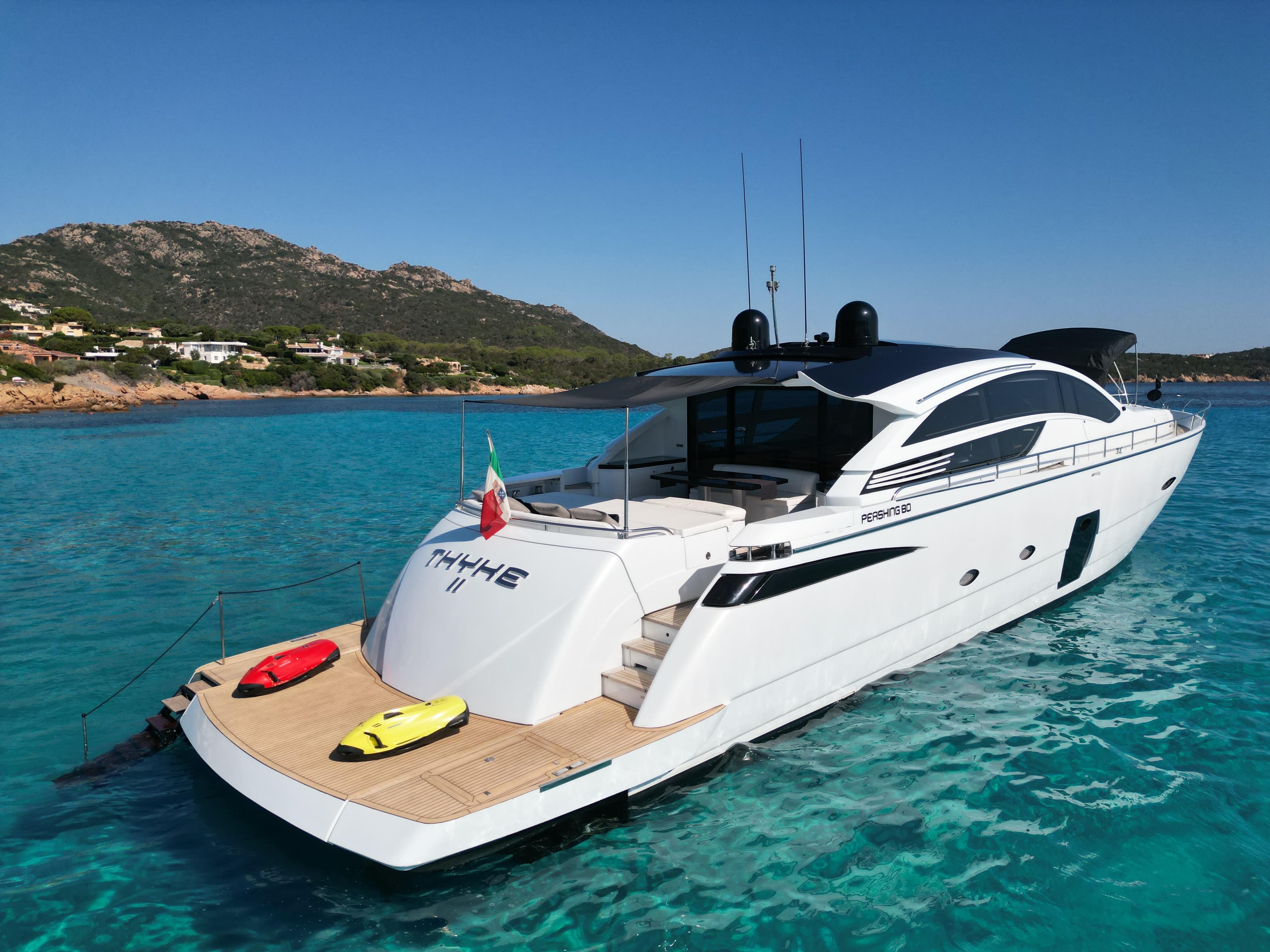 Luxury 2008 Pershing 80 yacht in turquoise waters, with scenic coastal backdrop.