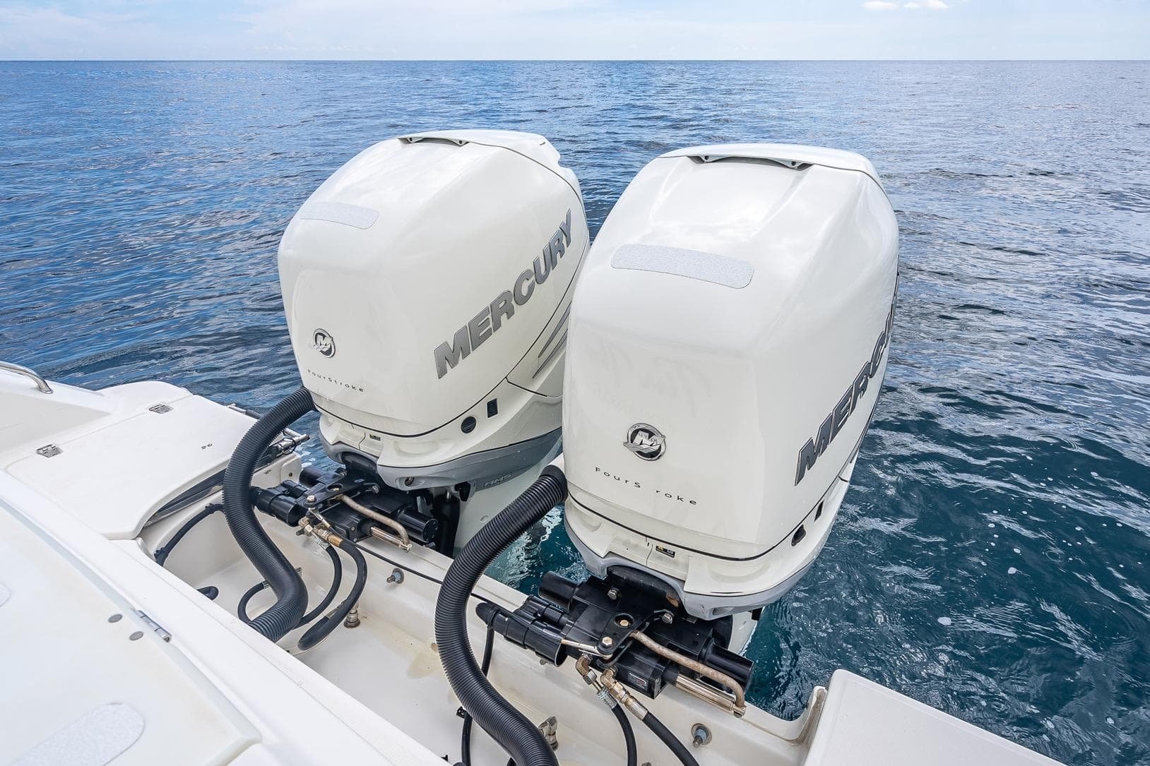 Twin Mercury outboard engines on a 2017 Boston Whaler 330 Outrage, ocean backdrop.