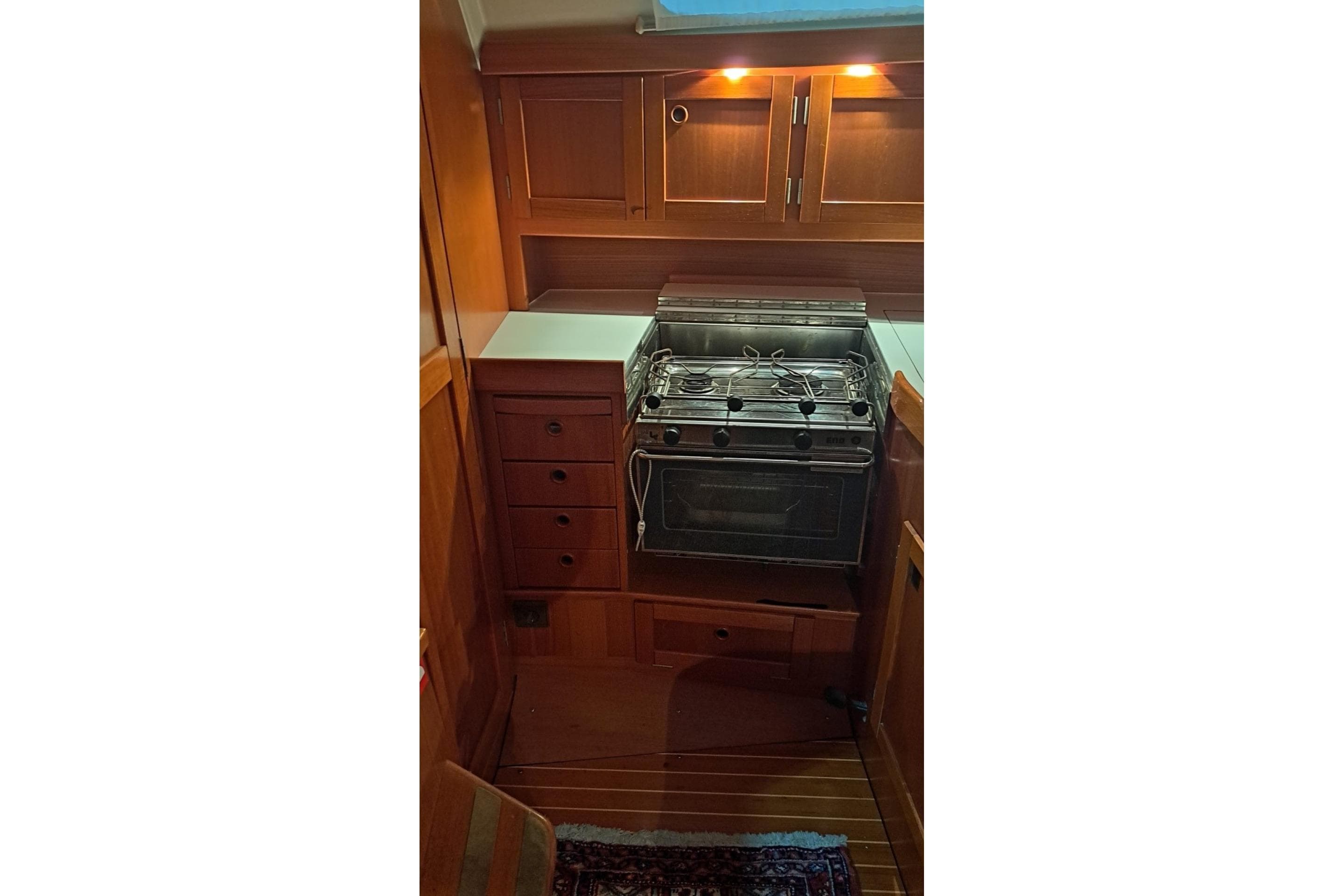 Cozy kitchen area in a 2002 Comfortina 35 yacht with wooden cabinetry and stove.