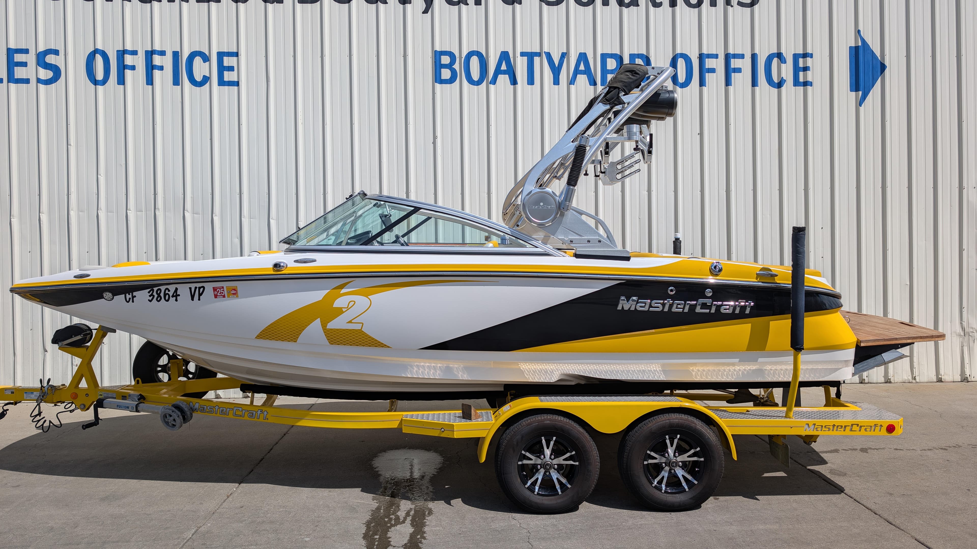 2013 MasterCraft X2 boat on trailer, parked outside a boatyard office.