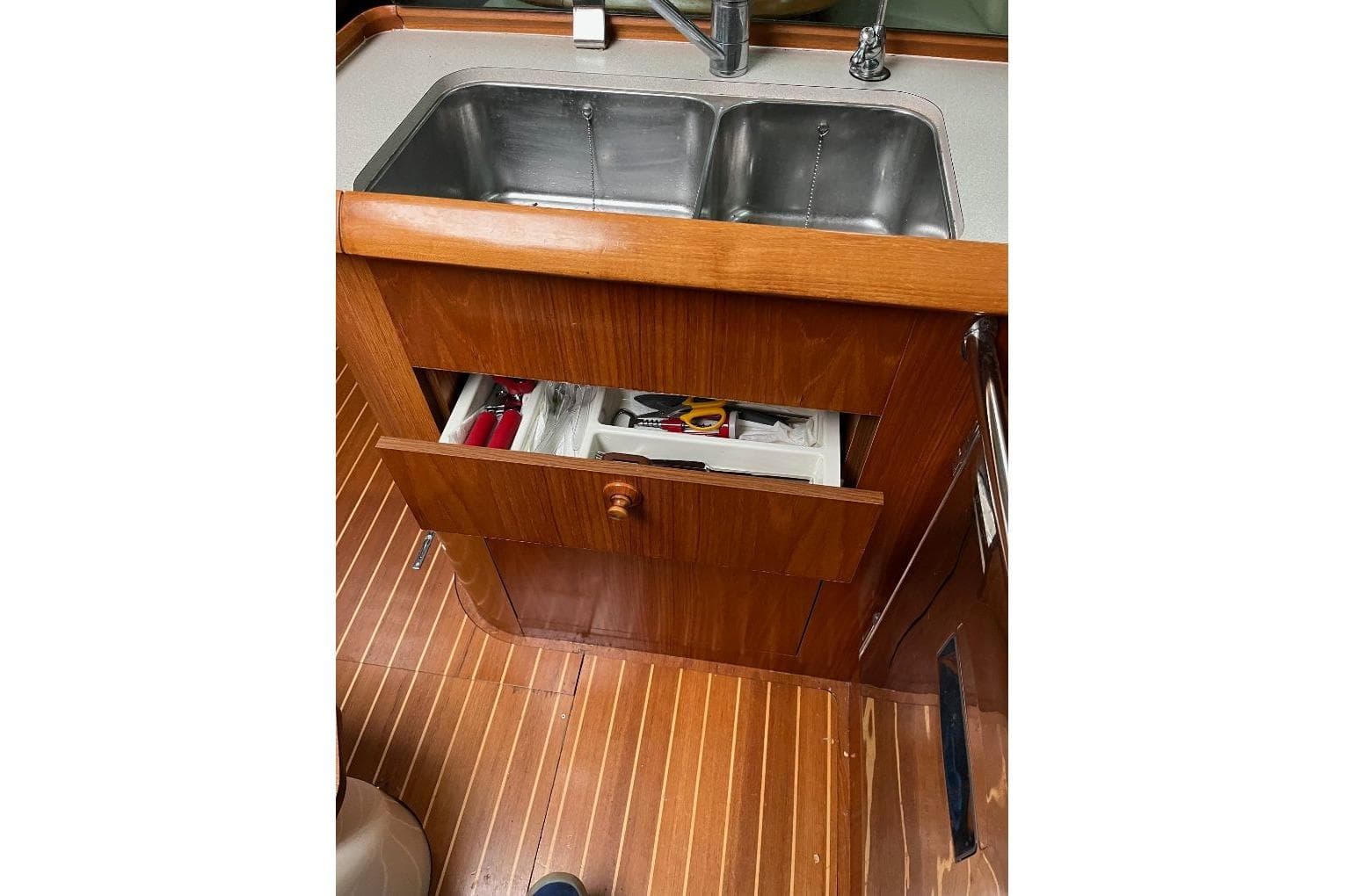 Wooden kitchen area with sink and open drawer on Jeanneau Sun Odyssey 45, 2008 model.