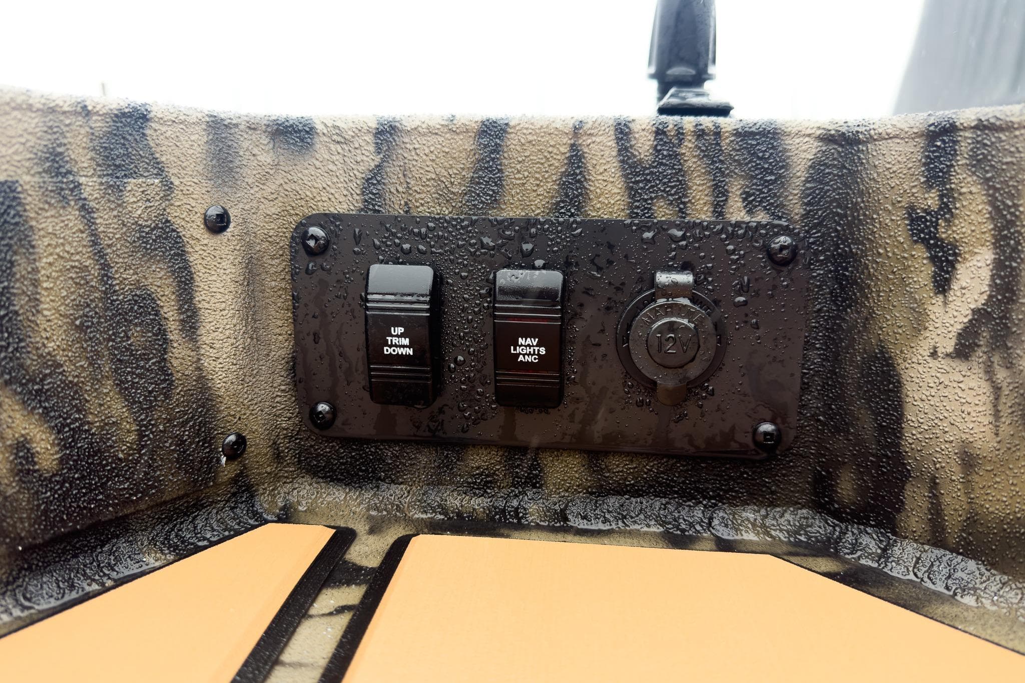 Control panel of Excel EX203C boat with switches and 12V outlet, wet surface.
