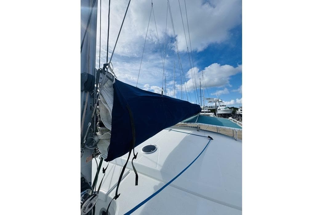2010 Fountaine Pajot Mahe sailboat deck with blue sail cover under a cloudy sky.