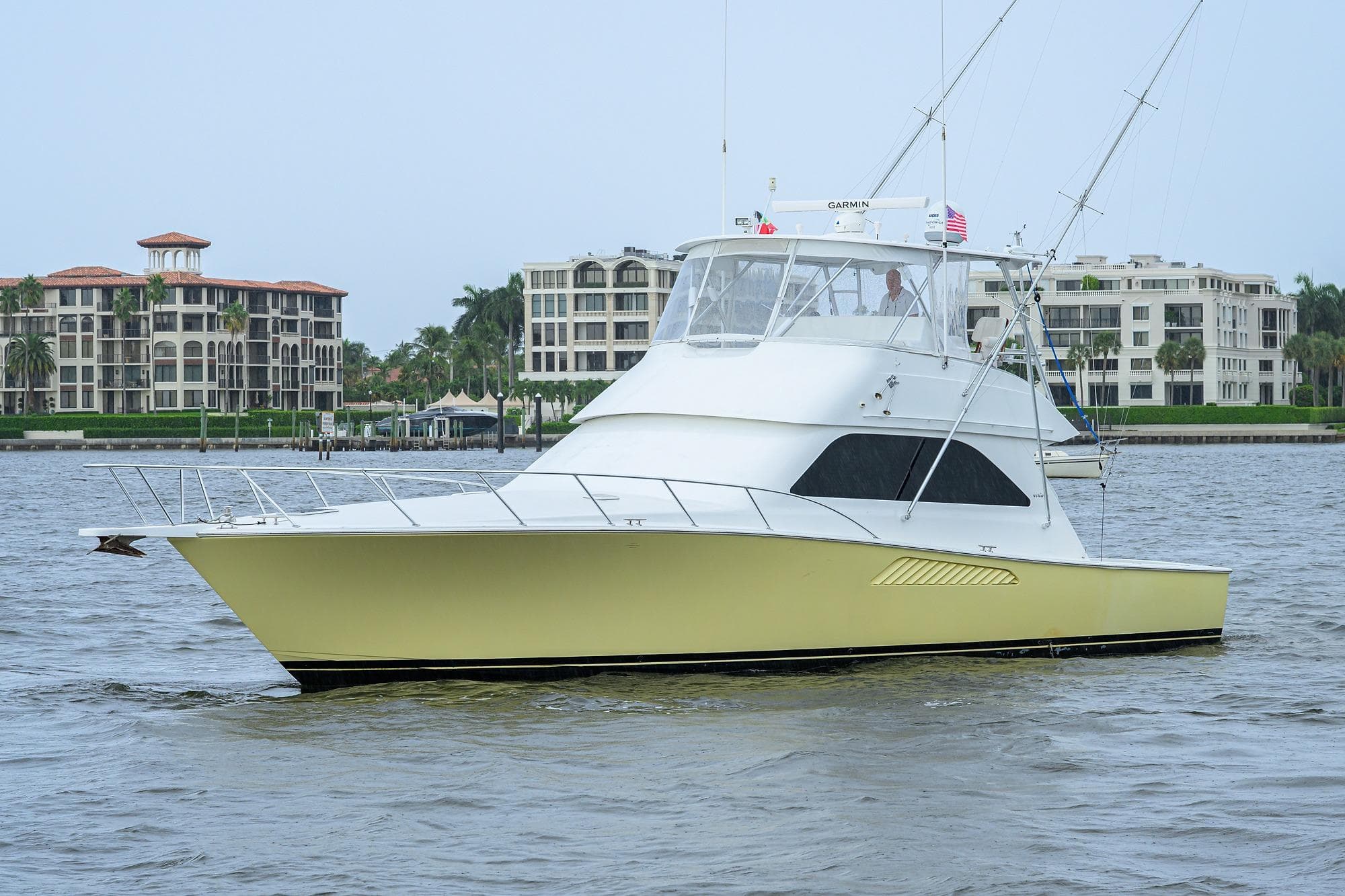2004 Viking 48 Convertible yacht cruising near waterfront buildings.