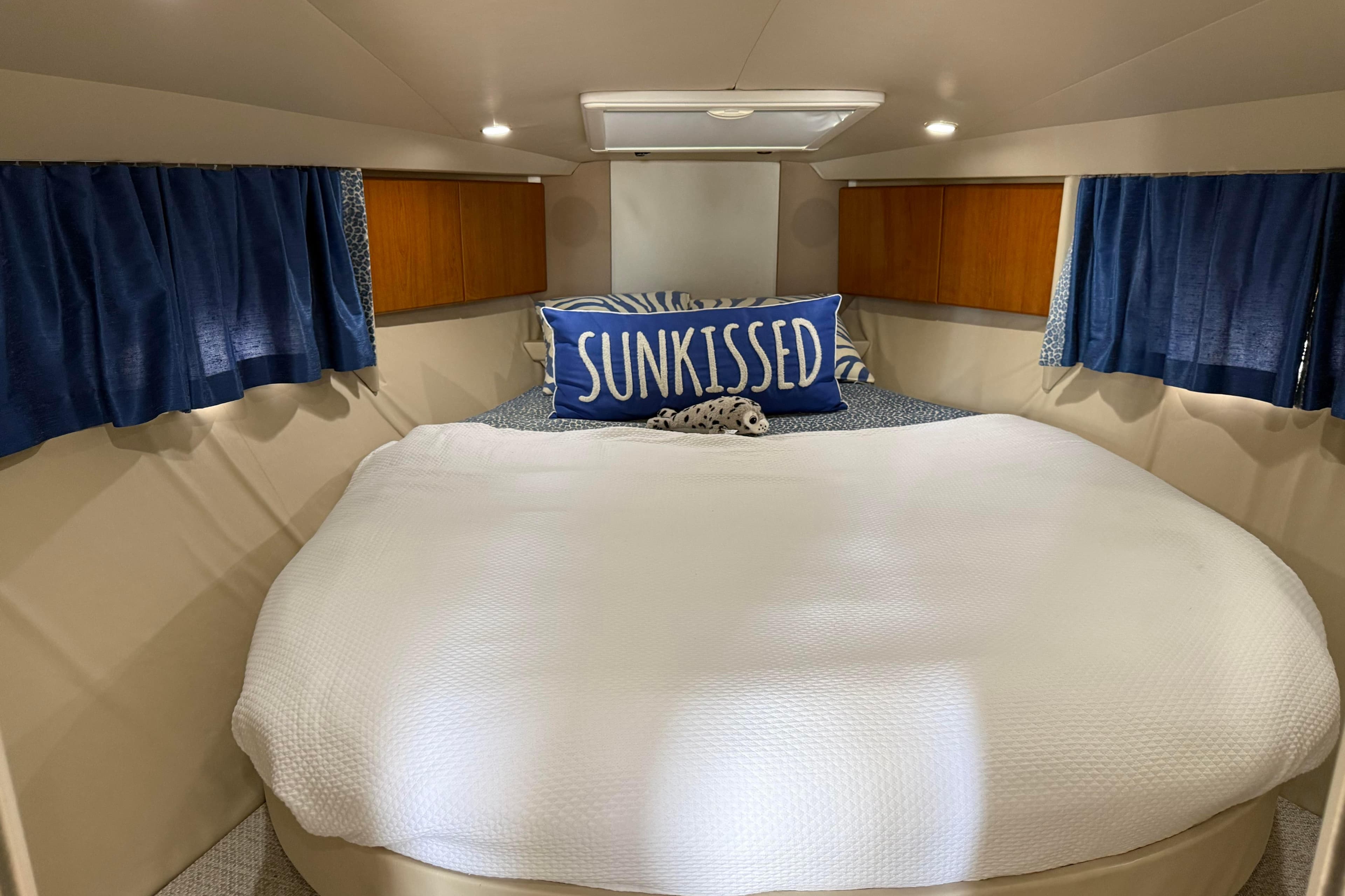 Cozy cabin interior of 2000 Formula 41 Performance Cruiser with "Sunkissed" pillow and blue curtains.
