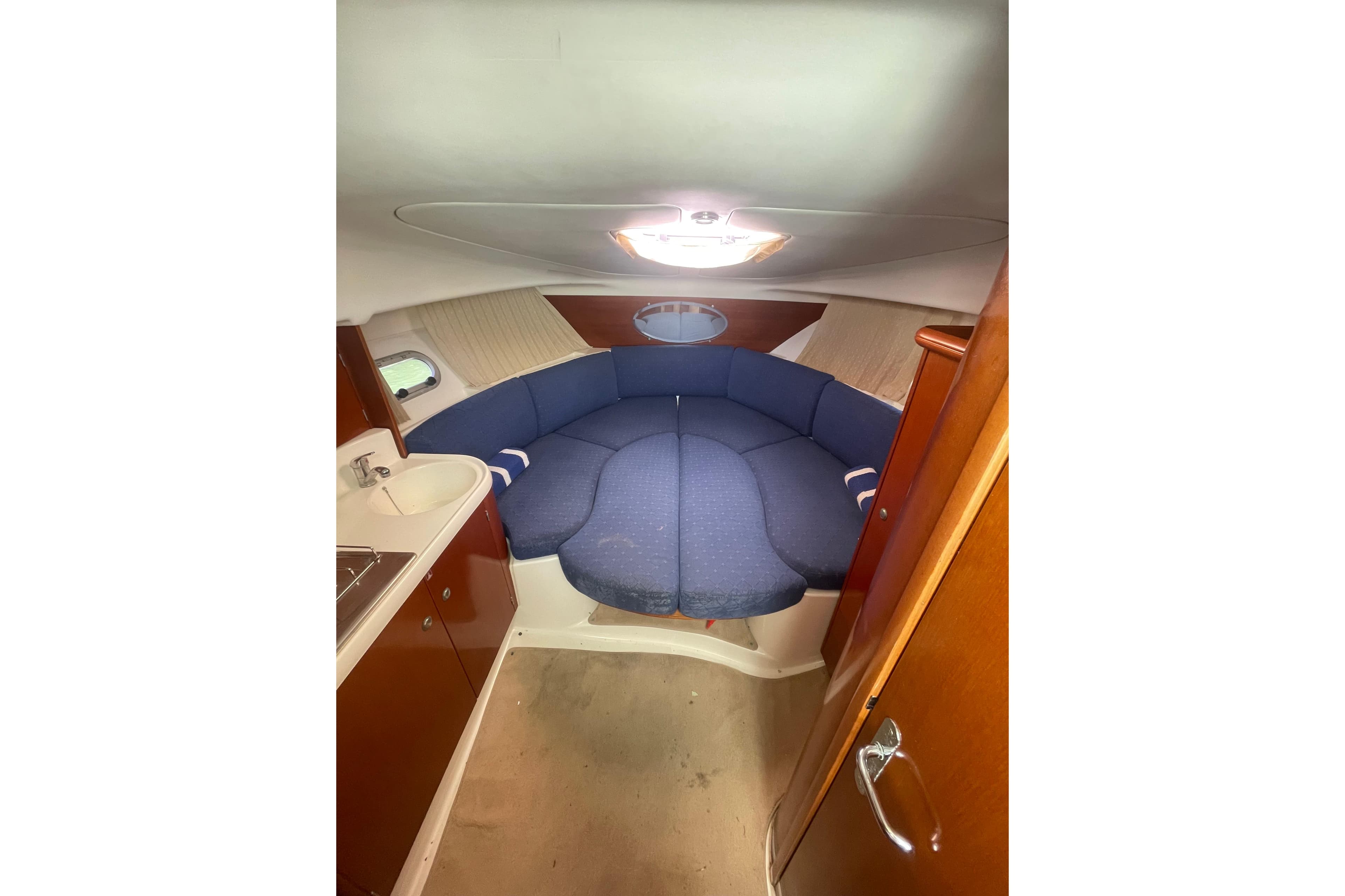 Interior of 2005 Jeanneau Leader 805 boat with blue seating and compact kitchenette.