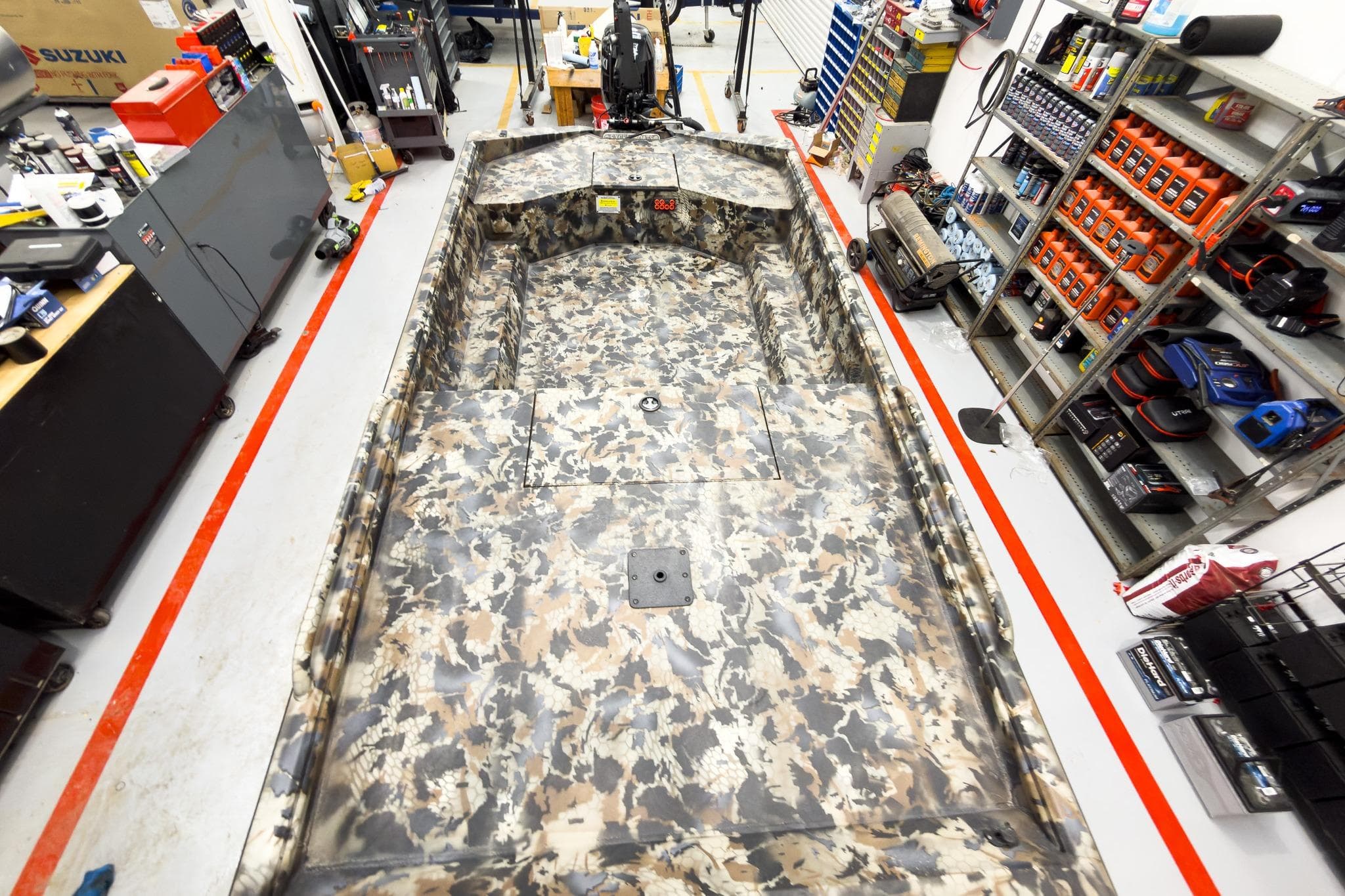 Camouflage-patterned Excel Eclipse boat in a workshop, surrounded by tools and equipment, 2026 model.