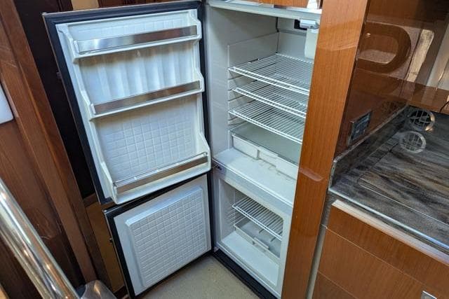 Open refrigerator inside 2013 Sea Ray 470 Sundancer yacht, featuring multiple shelves and door compartments.
