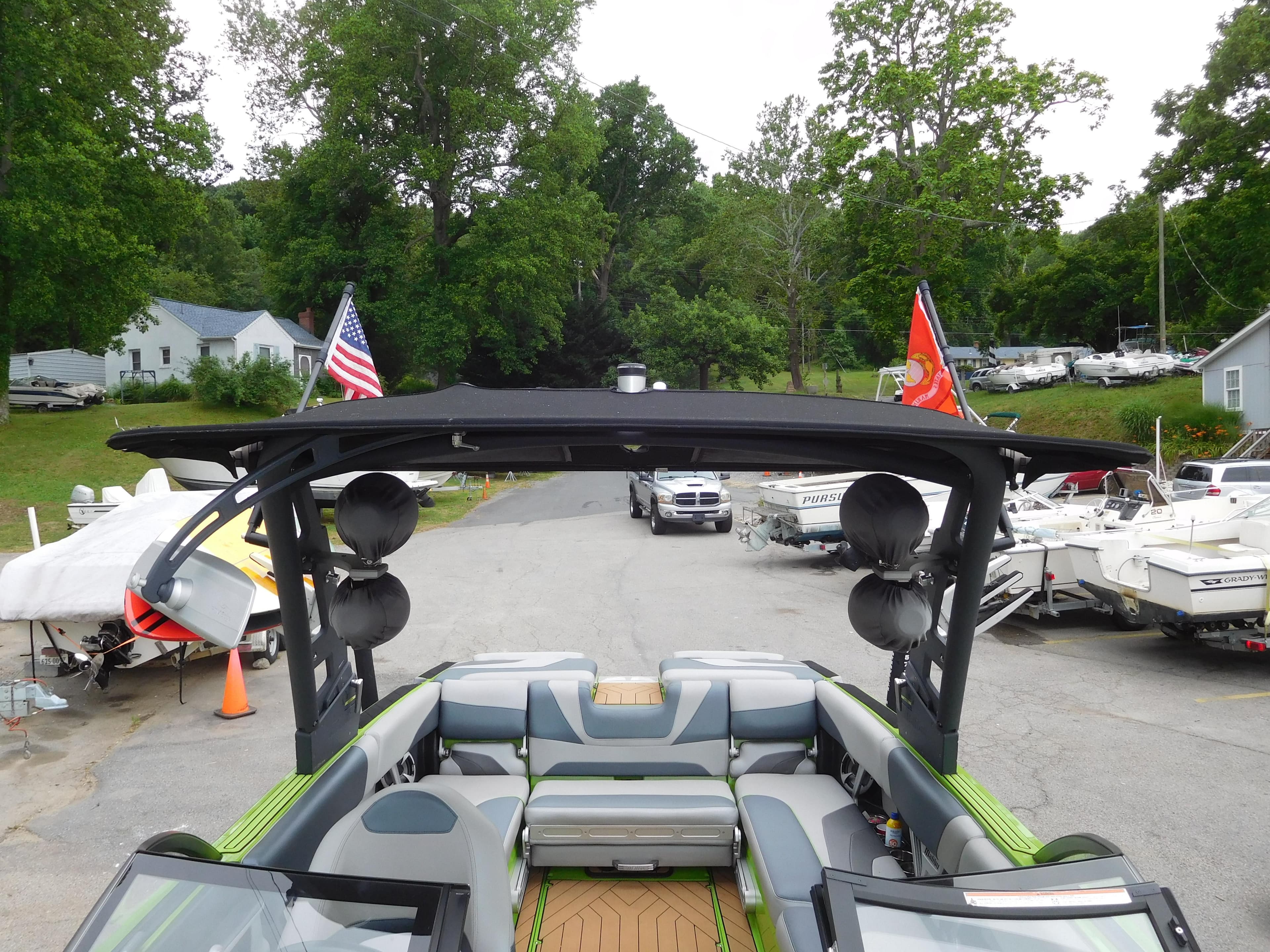 2017 Malibu Wakesetter 24 MXZ boat with tower speakers and flags, parked in a marina.