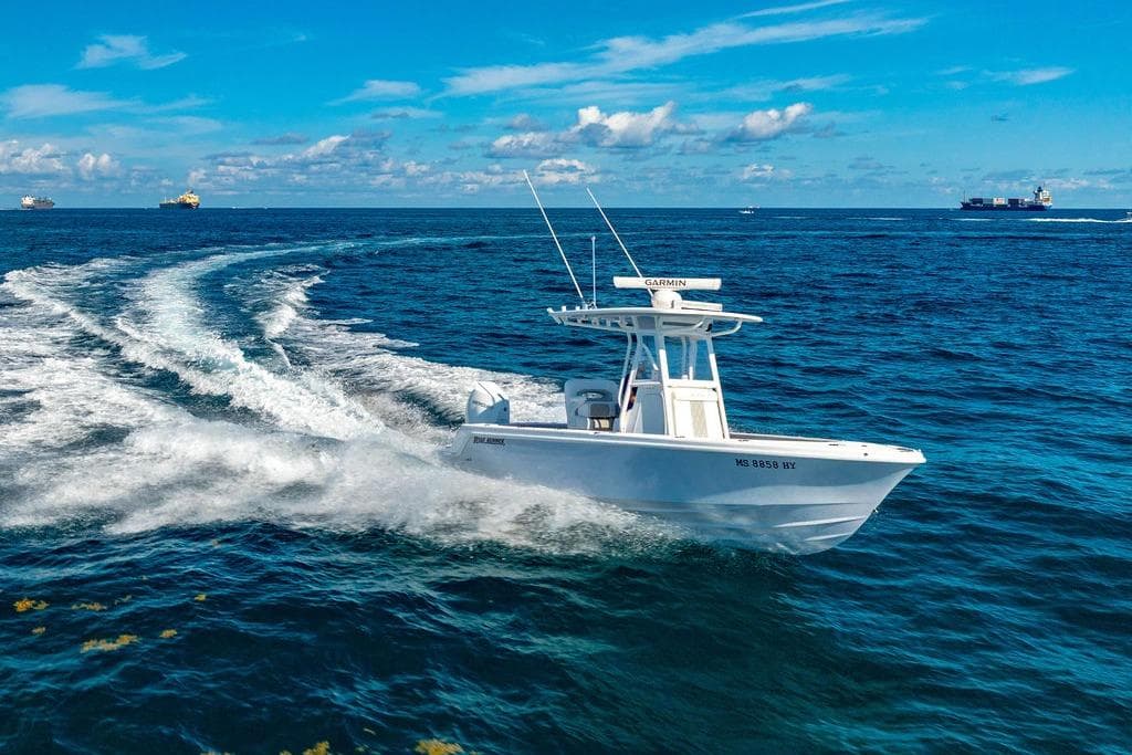 2024 Reef Runner 230 Open boat cruising on open ocean under clear blue sky.