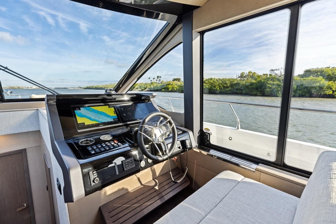 Interior helm of 2026 Cruisers Yachts 50 Fly with navigation screens and river view.
