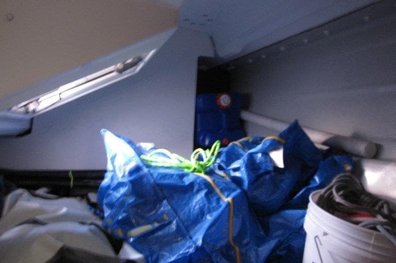 Interior storage area of 2022 Jeanneau Sun Odyssey 349 sailboat with blue tarp and equipment.