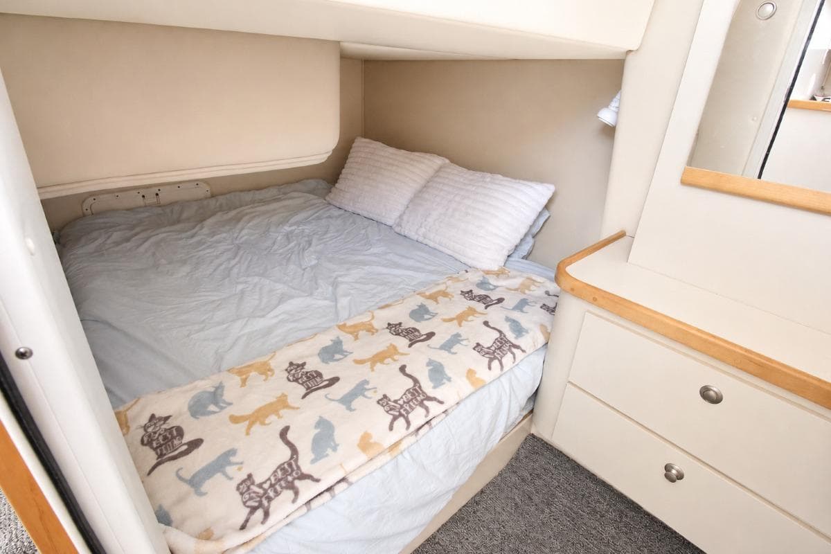 Cozy cabin bedroom in 1996 Cruisers Yachts 3580 Flybridge with cat-themed blanket.
