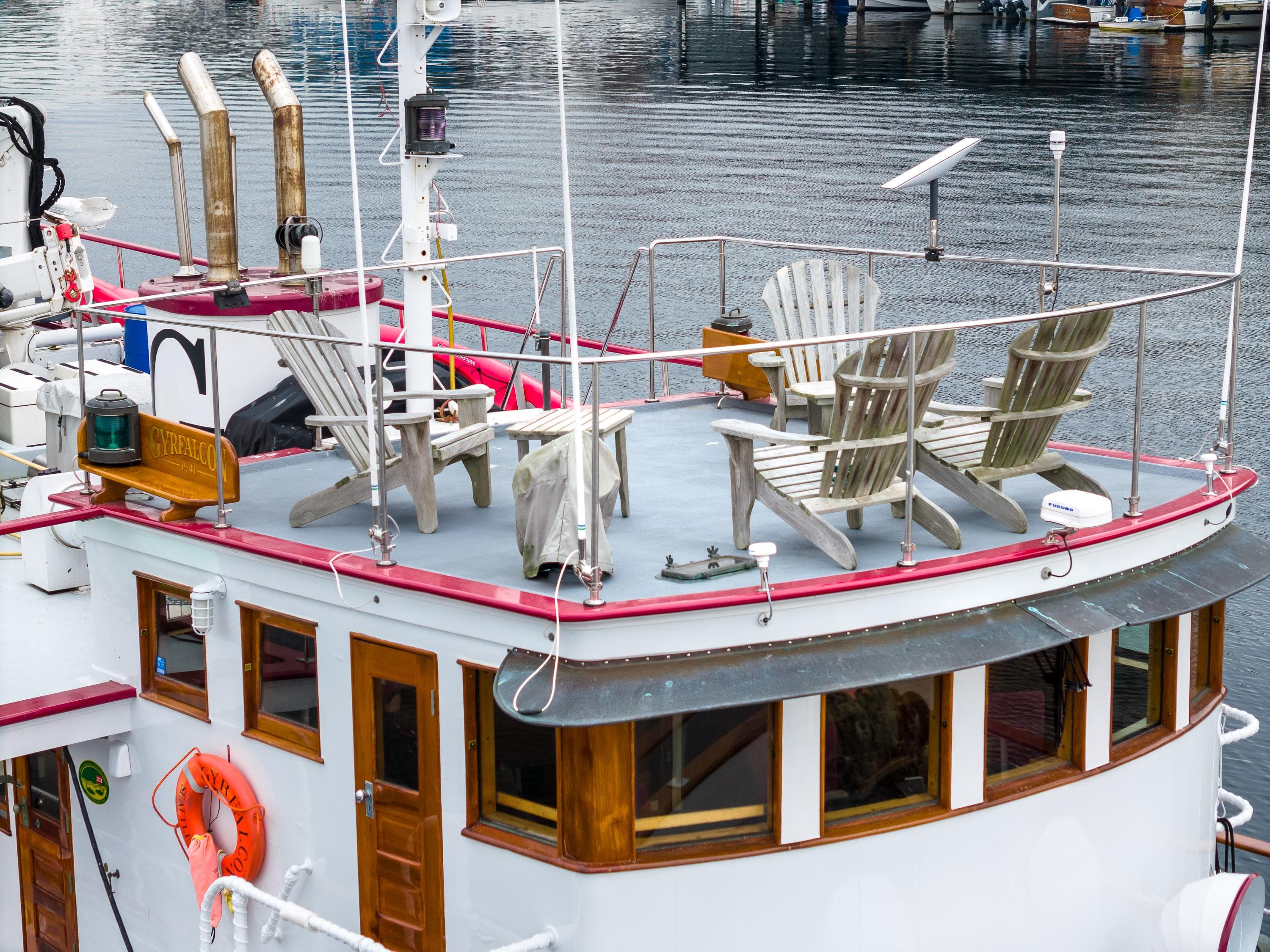 1941 Custom Sagstad Fantail boat with deck chairs, docked on calm water.