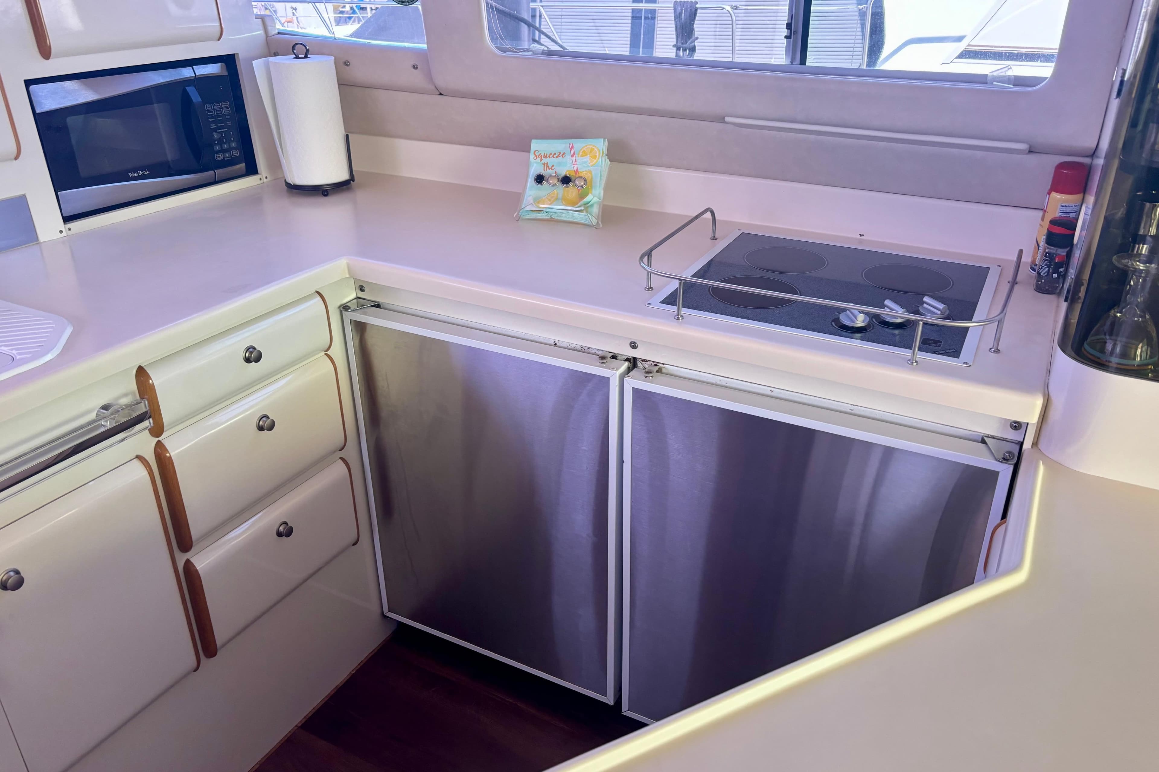 1995 Sea Ray 550 Sedan Bridge kitchen with stove, microwave, and storage cabinets.
