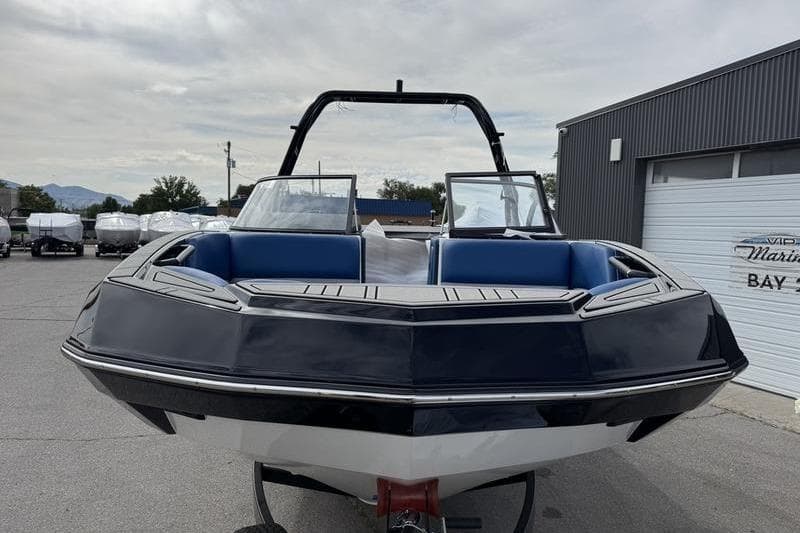 2025 Moomba Max boat with blue seating, parked outdoors near a marina.