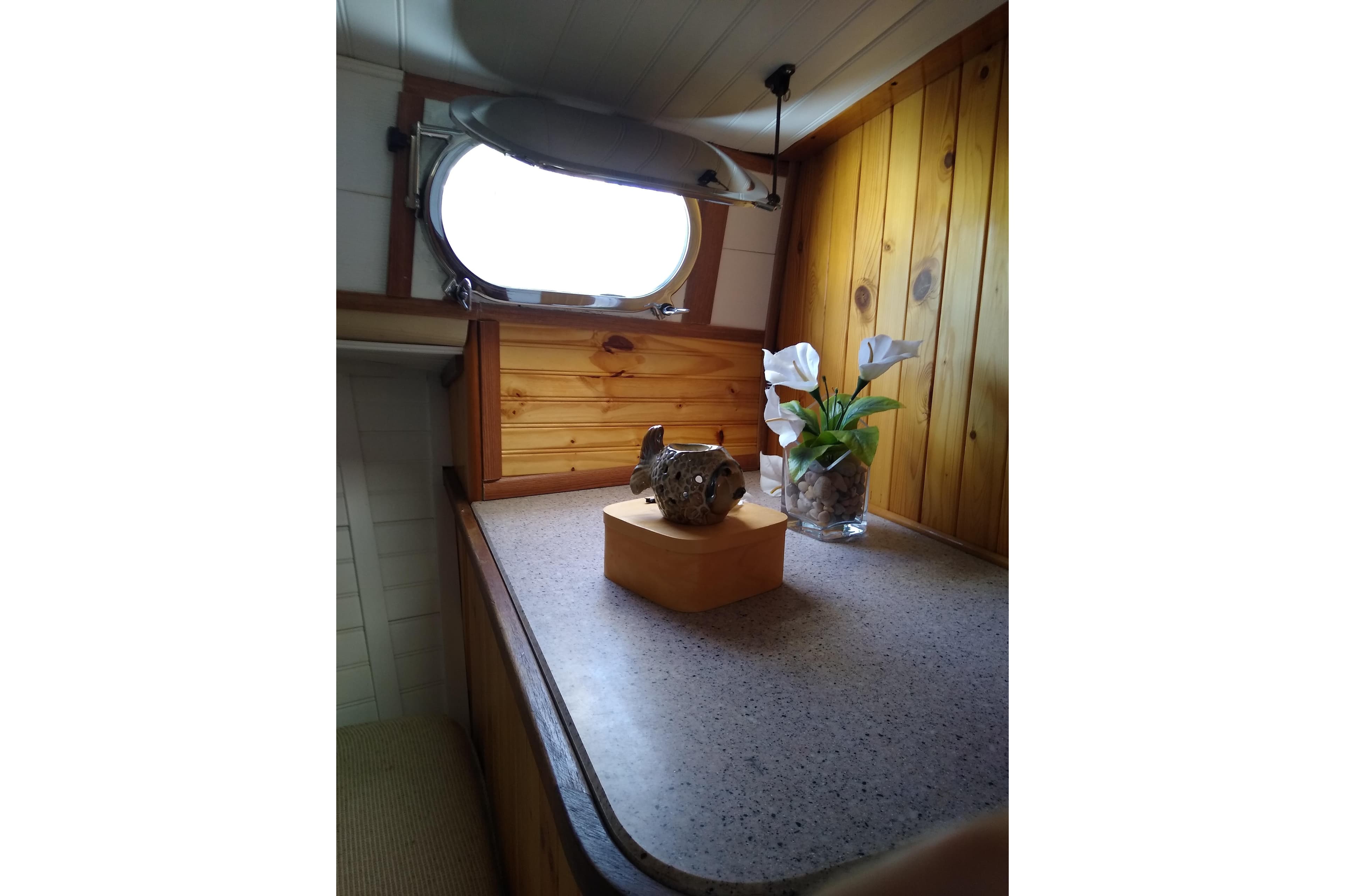 Cozy interior of 1979 Mainship 34 Custom Sedan with wooden paneling and decorative flowers.