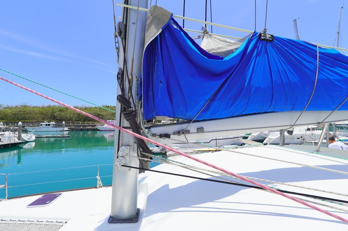 Lagoon 380 catamaran sailboat with blue sail cover, docked in a marina, 2013 model.