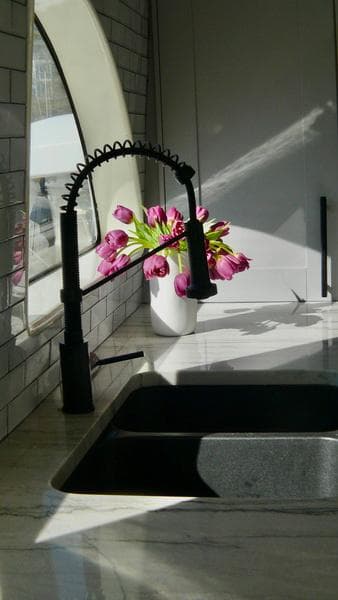 Modern kitchen sink with black faucet and pink flowers on Cheoy Lee 66 Pilothouse yacht.