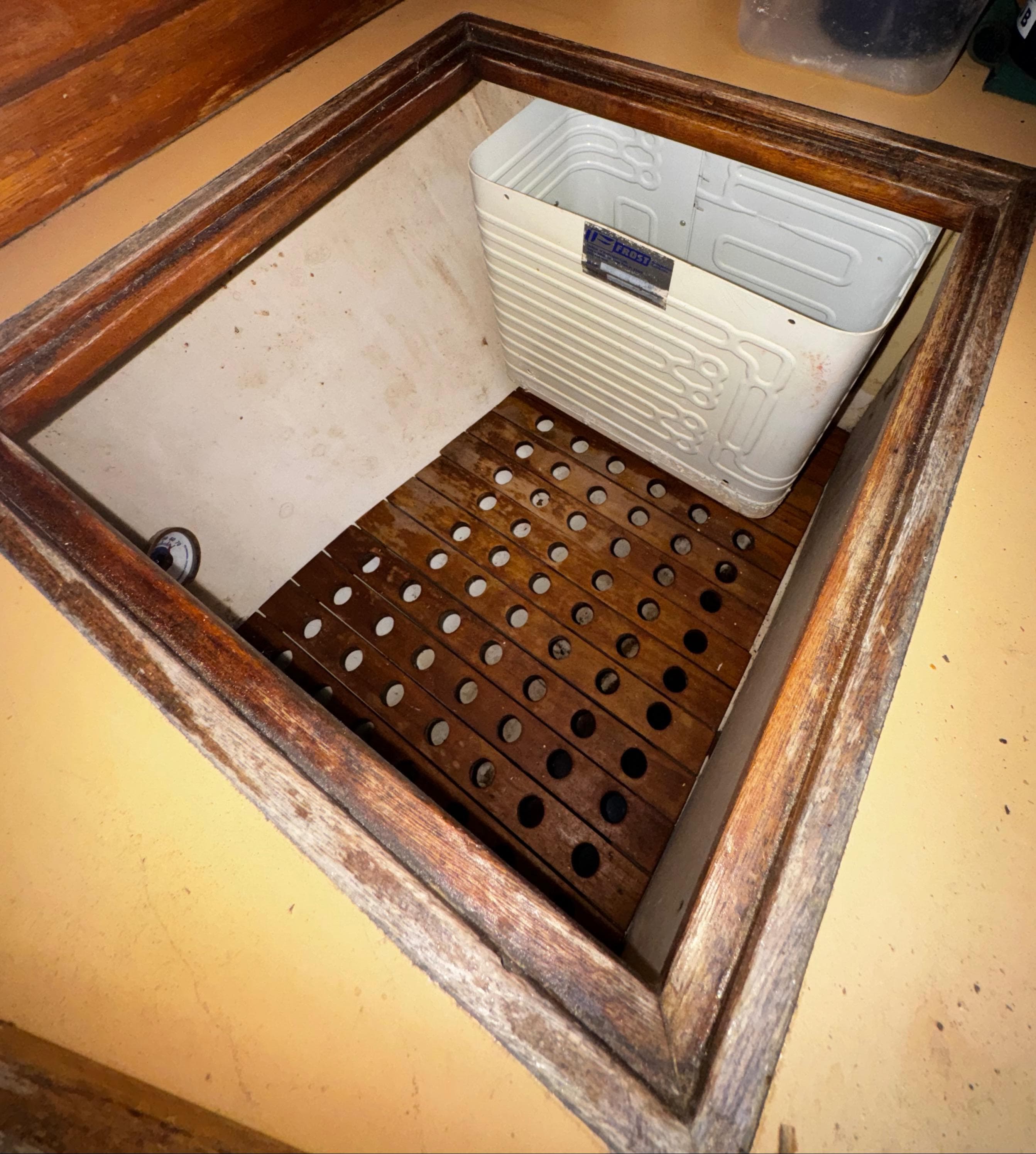 1985 Herreshoff 38 Cat Ketch interior storage compartment with wooden slats and white panel.