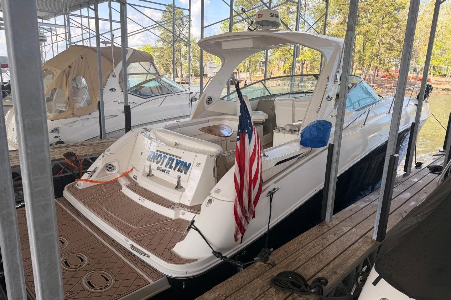 2010 Sea Ray 370 Express Cruiser docked with American flag, surrounded by trees.