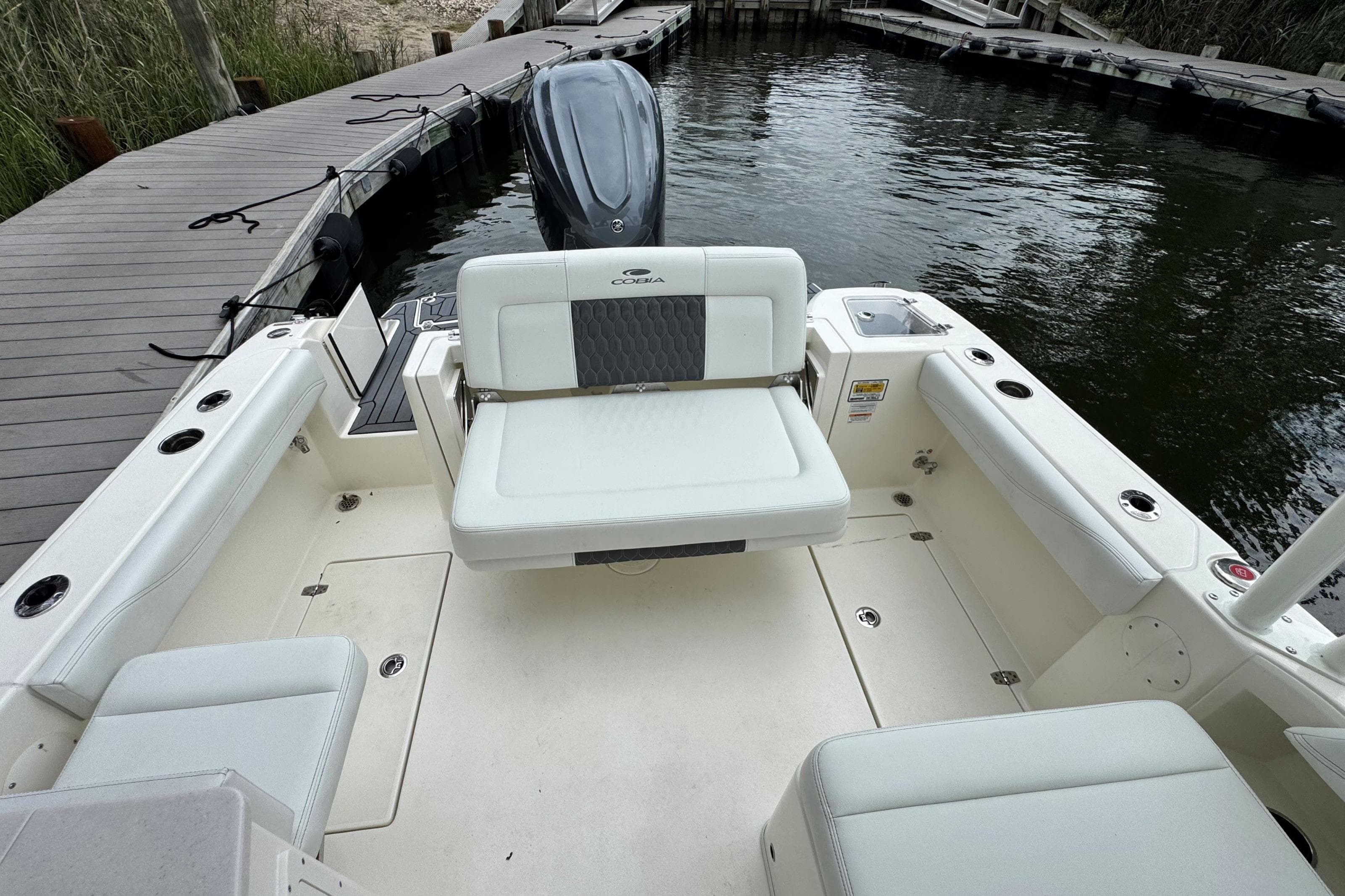 2026 Cobia 240 Dual Console boat interior with seating, docked by the water.