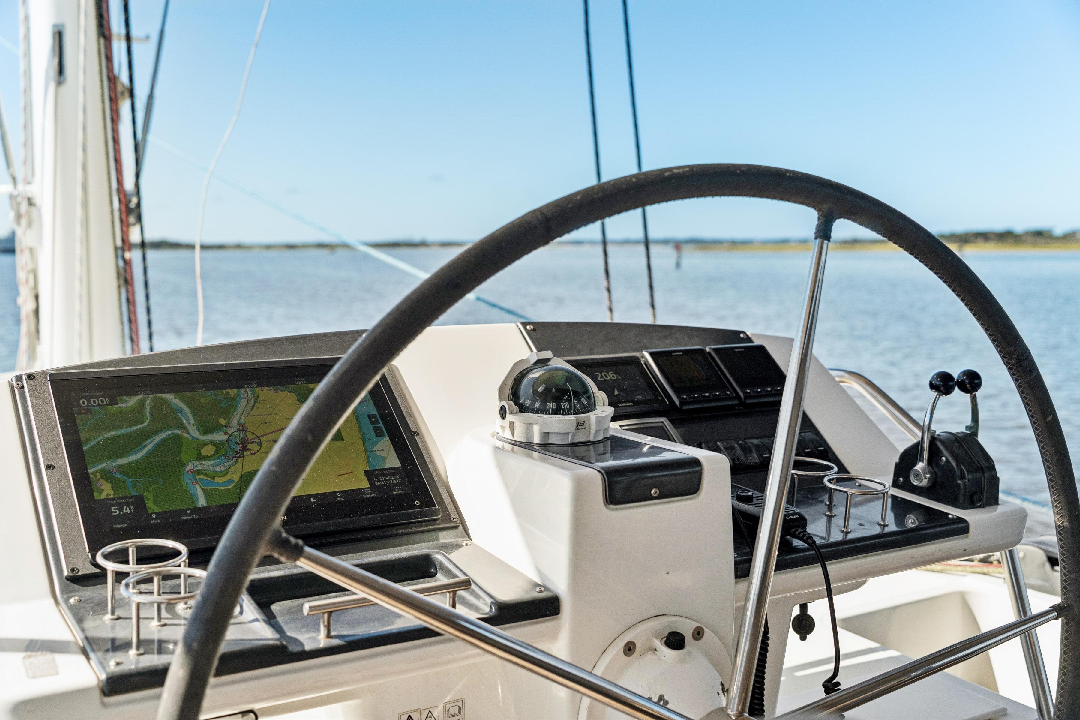 Steering wheel and navigation system on 2012 Lagoon 560 yacht, overlooking calm waters.