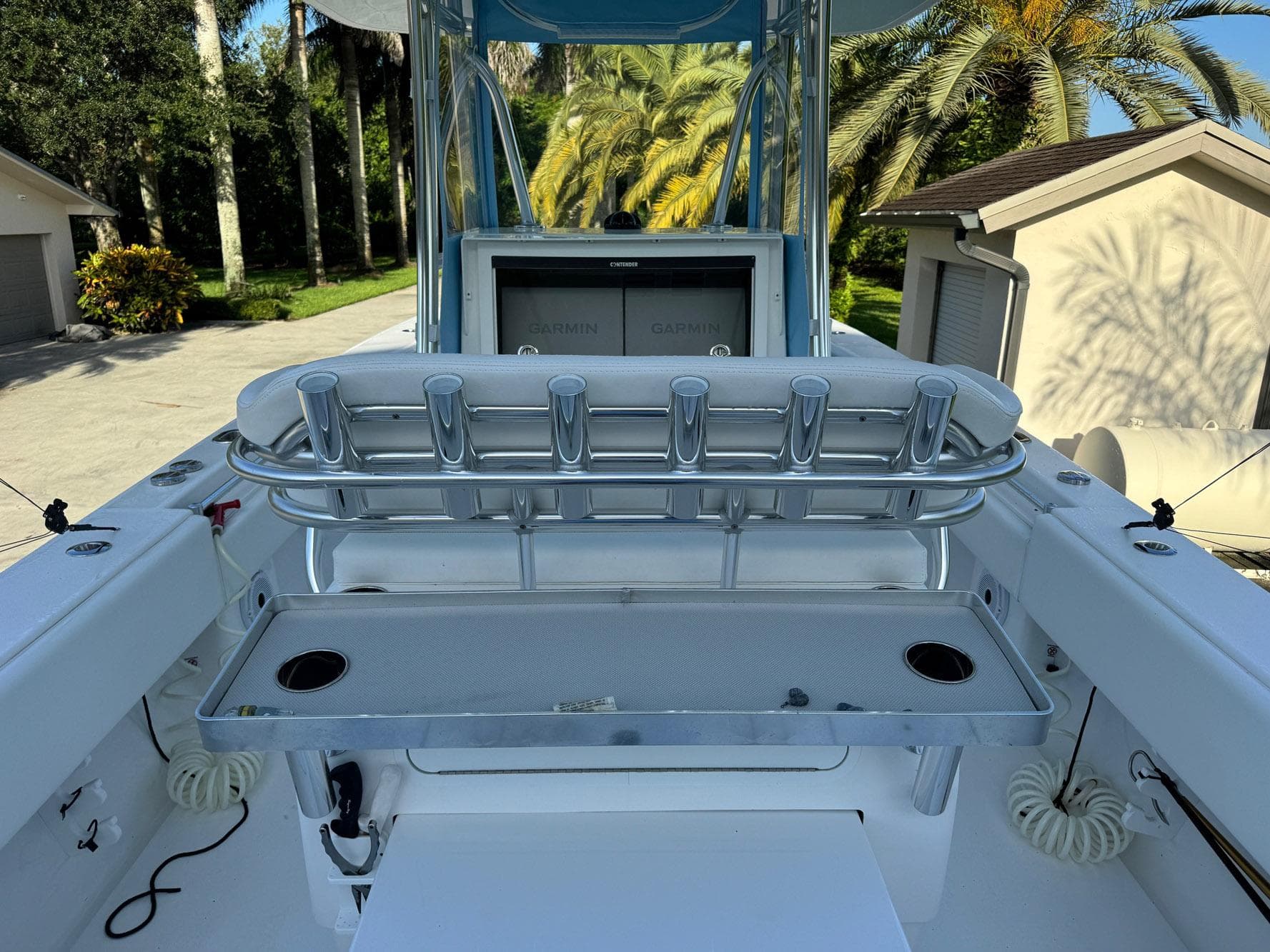 2024 Contender 32 ST boat interior with rod holders and console, surrounded by lush greenery.