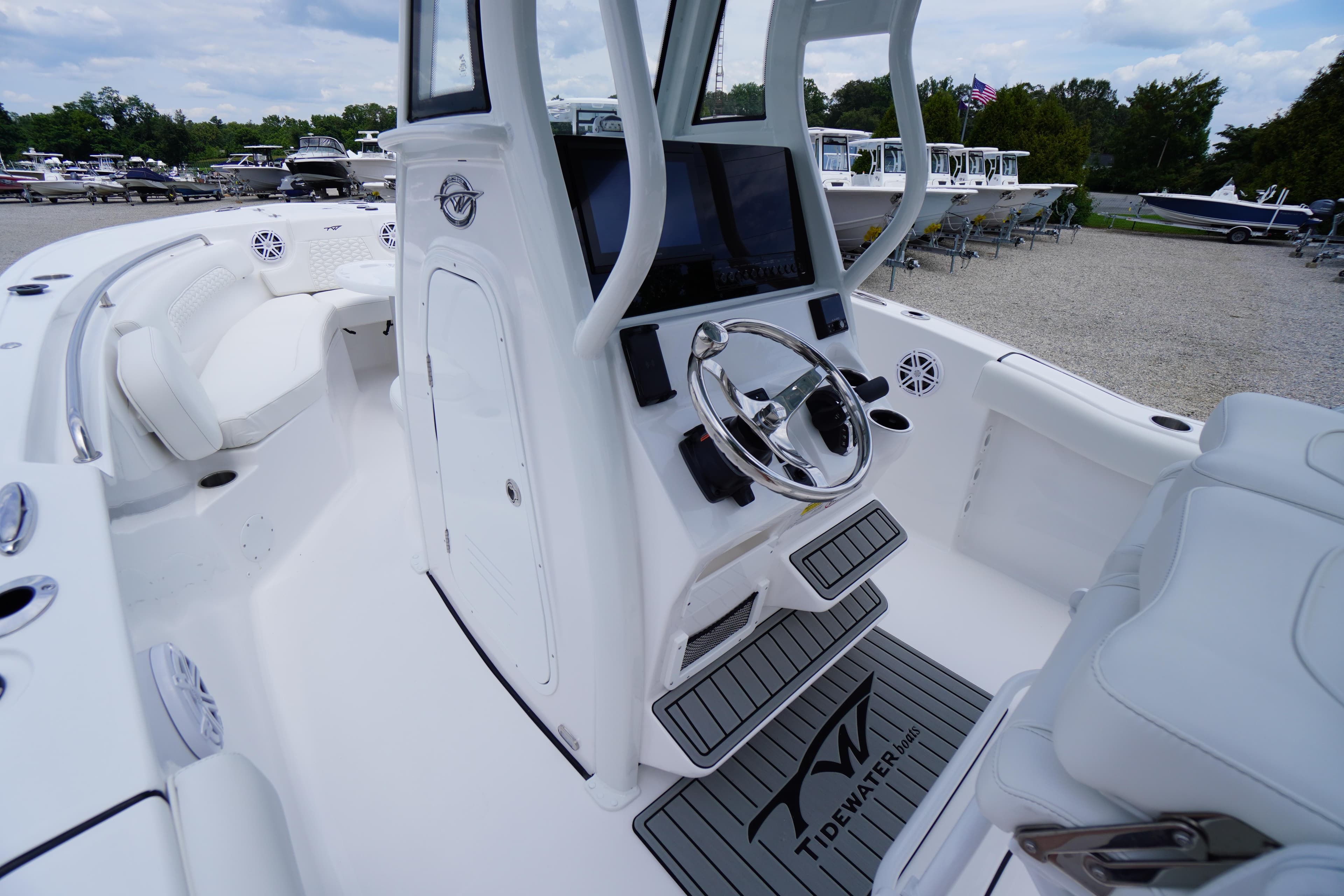 2026 Tidewater 232 SS boat interior with steering wheel and seating, docked outdoors.
