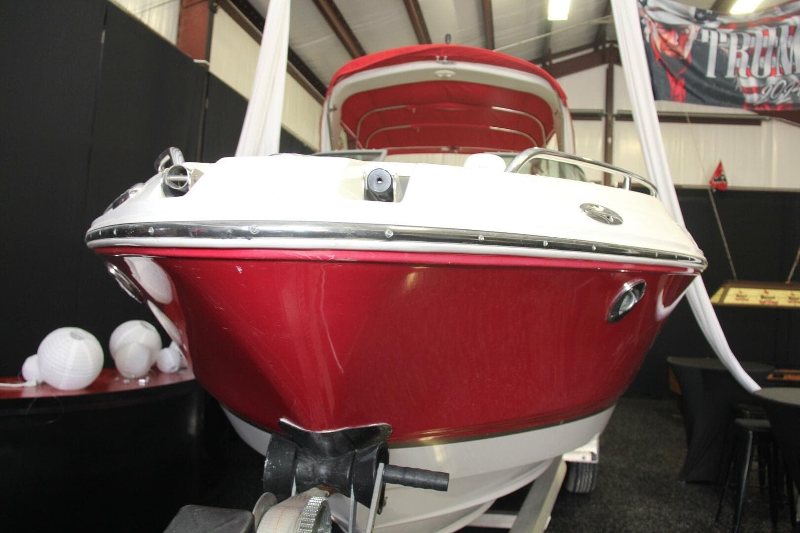 2006 Chaparral 256 SSi boat with red and white exterior in indoor showroom.