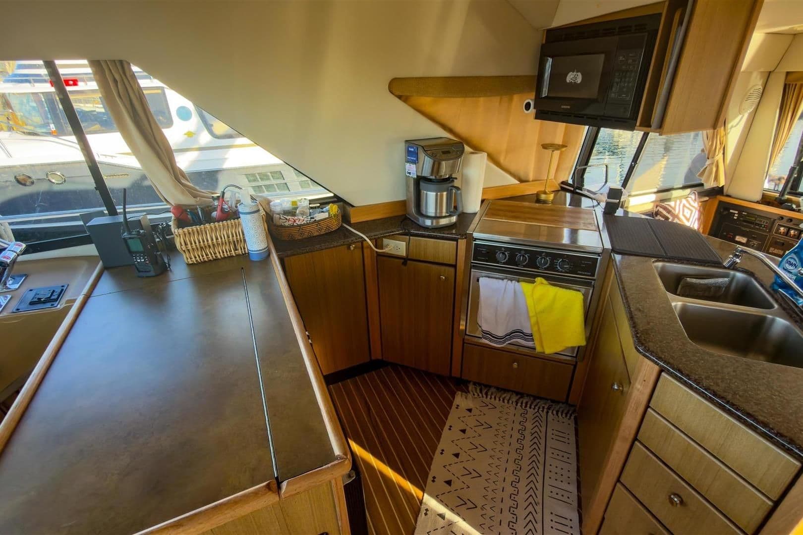 Interior of 2002 Bayliner 3988 Command Bridge Motoryacht kitchen with appliances and wooden cabinetry.