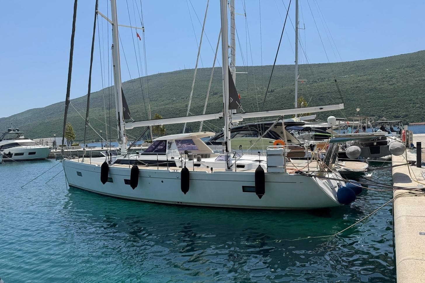 Sailing yacht Amel 55, 2017 model, docked in a marina with scenic mountain backdrop.