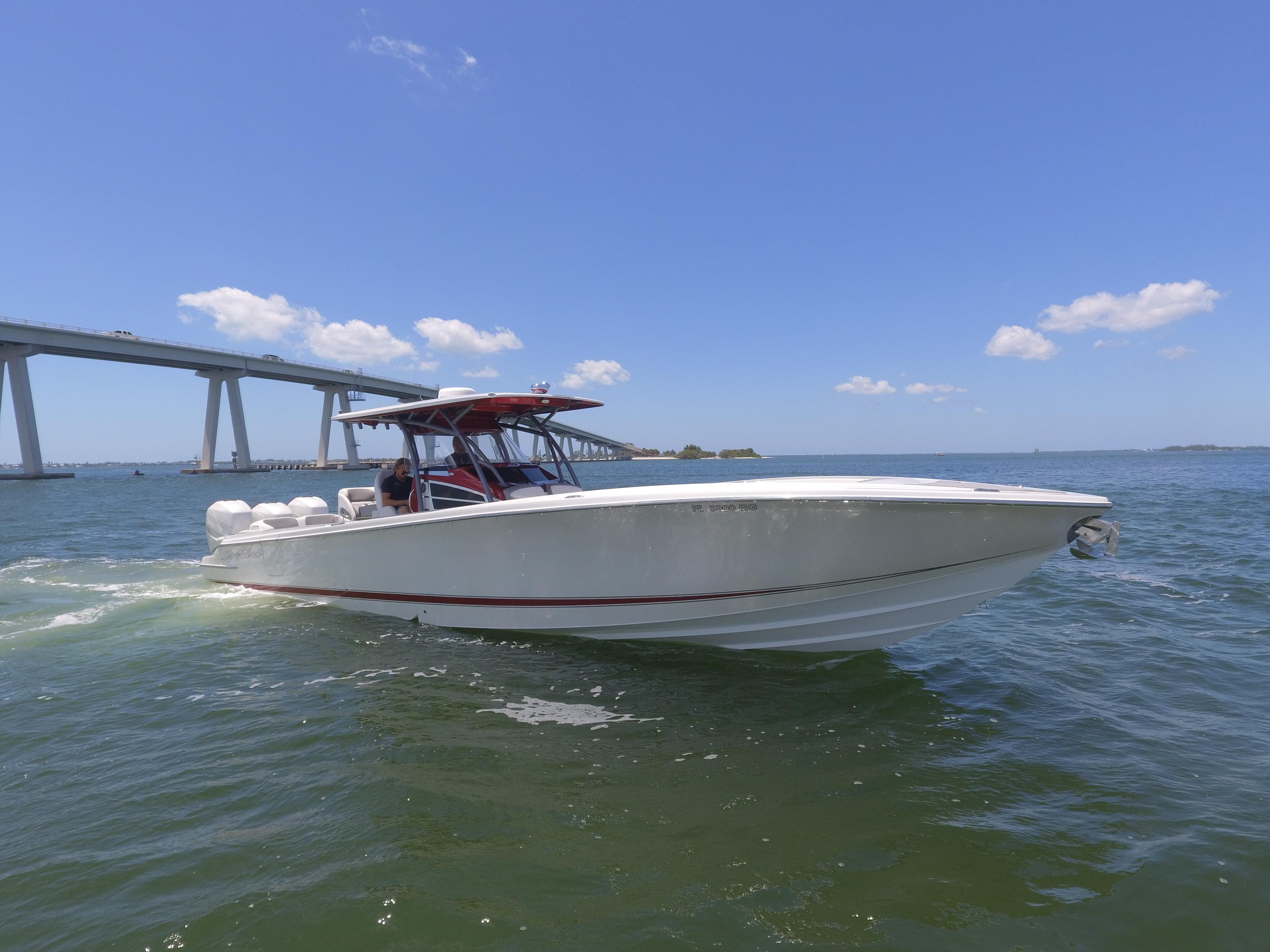 2017 Nor-Tech 390 Sport boat cruising on a sunny day near a bridge.