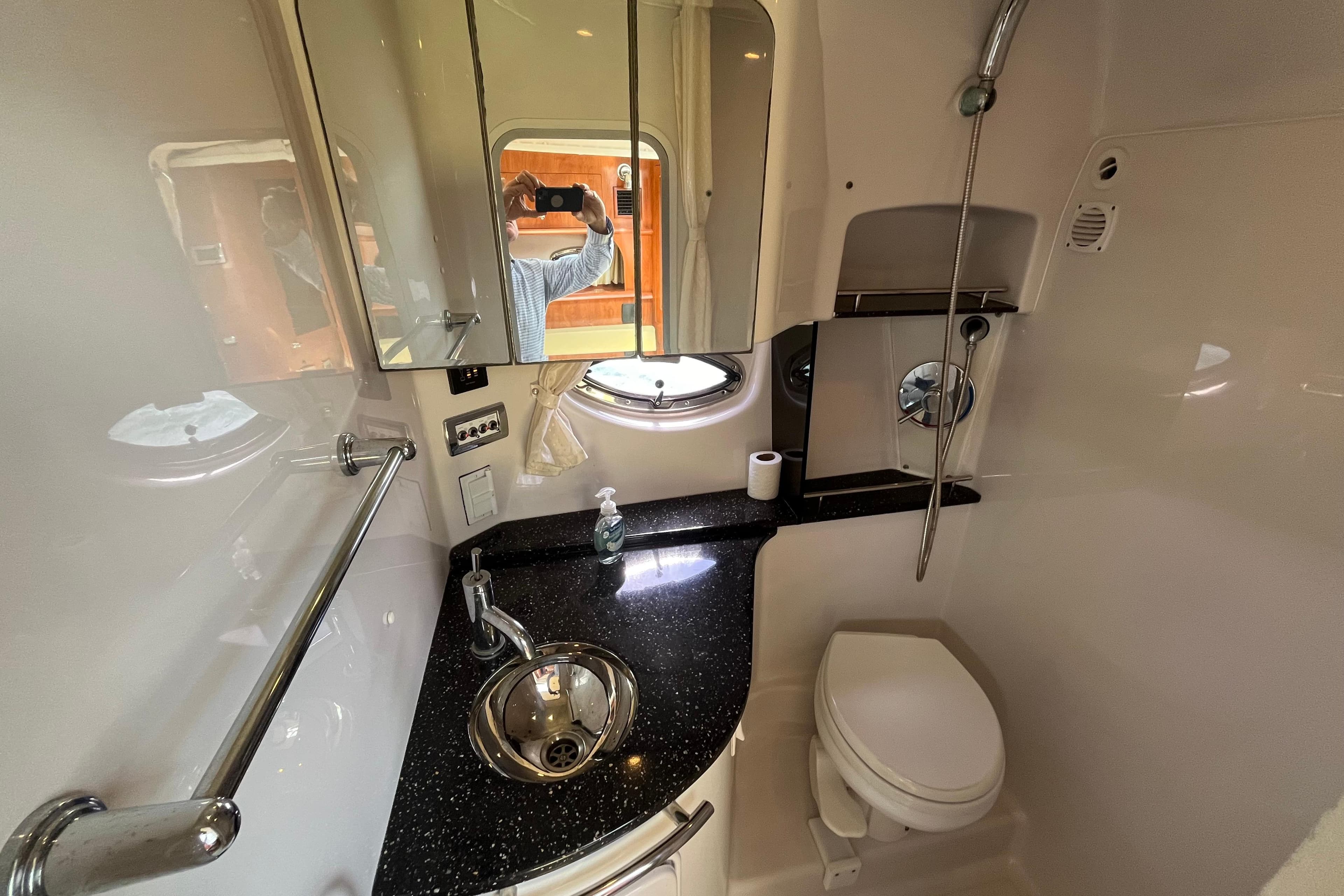 Compact bathroom in 2008 Four Winns 338 Vista yacht with sink, toilet, and mirror.