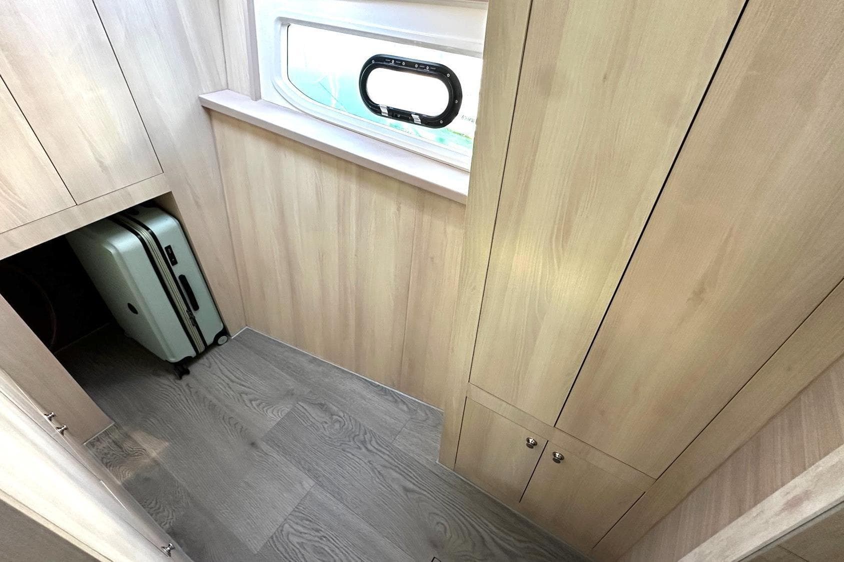 Interior of 2025 Aquila 44 Yacht with wooden paneling and suitcase storage.