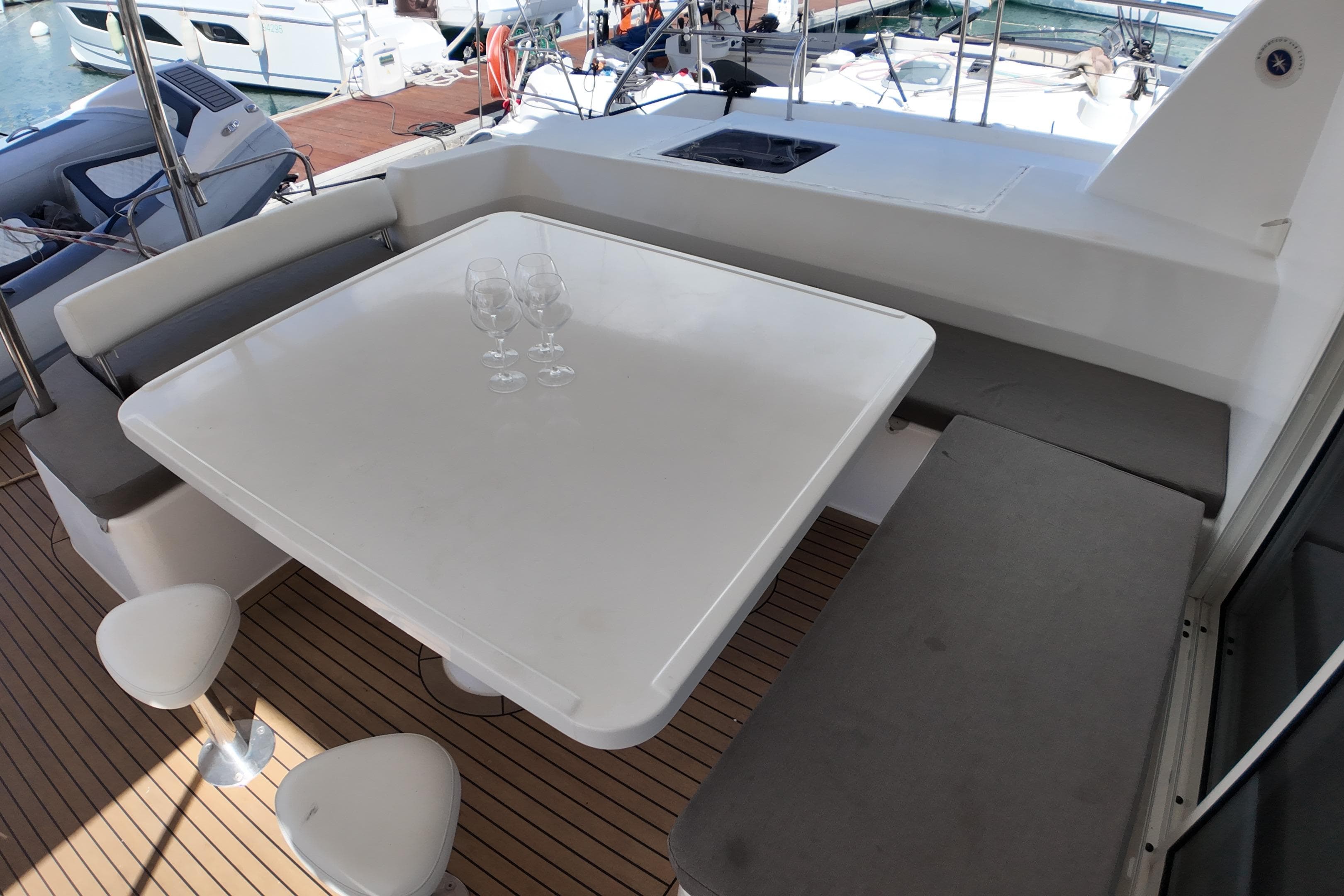 Outdoor seating area on 2017 Leopard 51 Powercat with table and wine glasses.