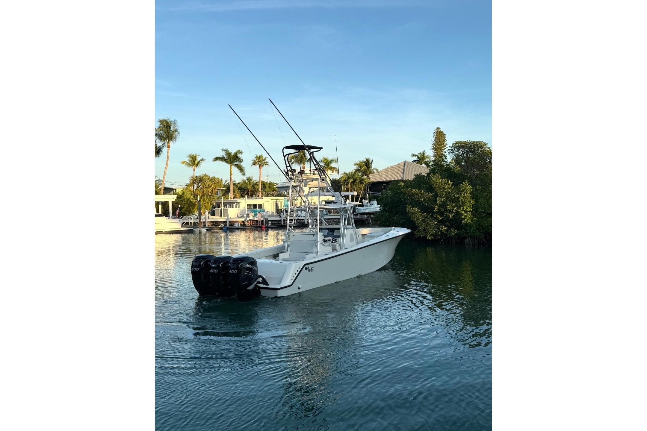 2015 SeaVee 390Z boat with triple engines on a calm waterway, surrounded by palm trees.