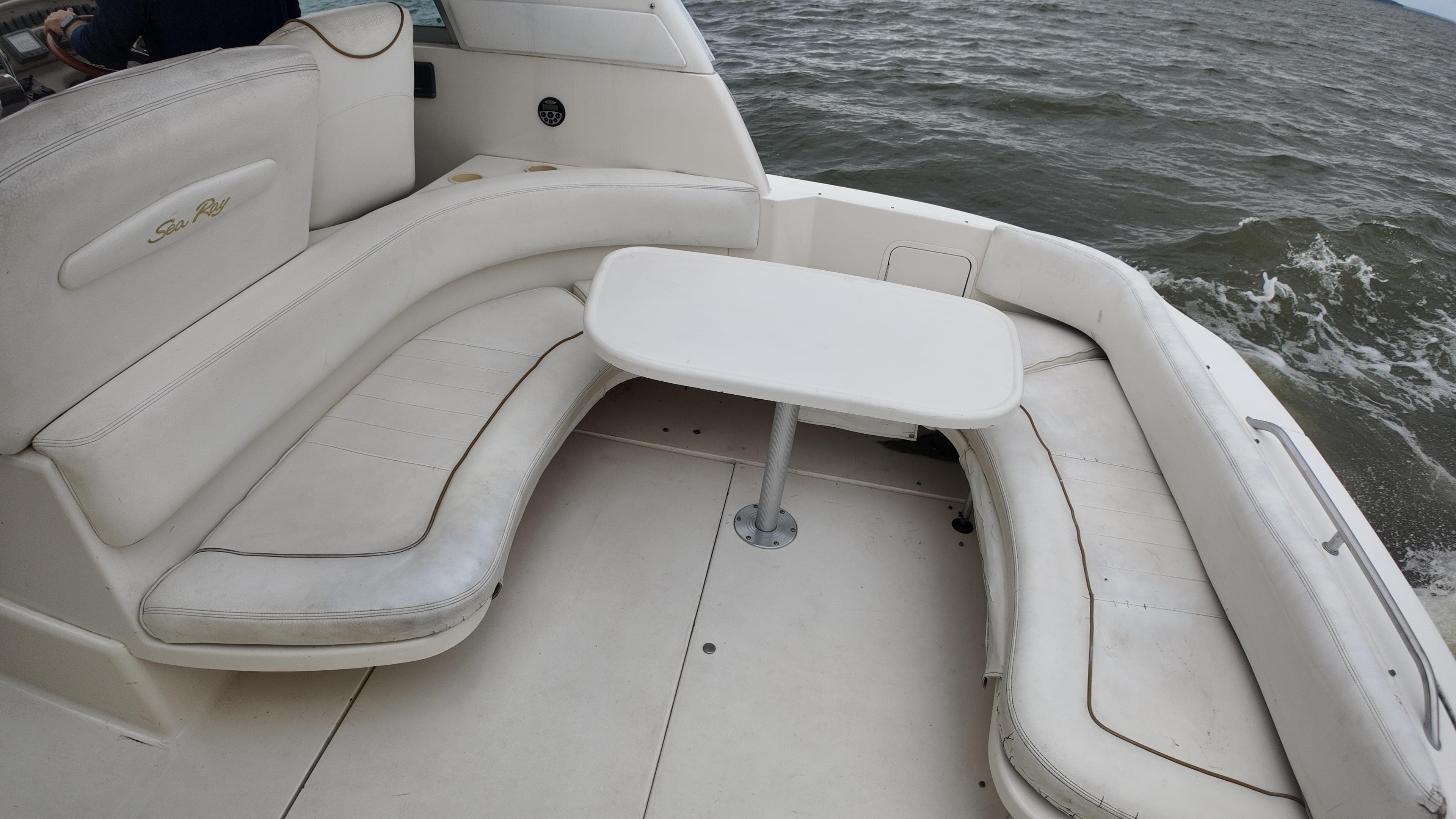 1999 Sea Ray 310 Sundancer boat interior with white seating and table on open water.
