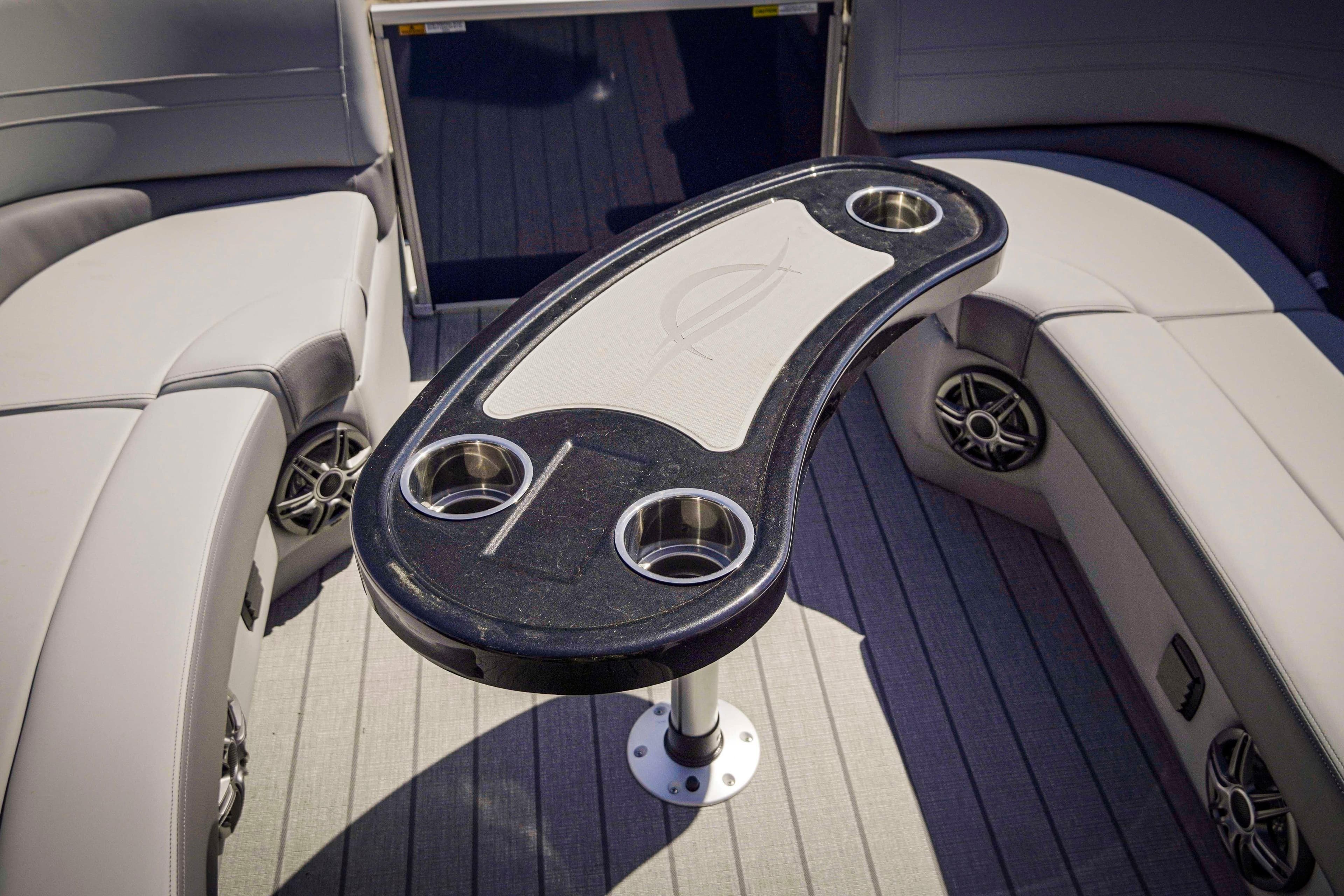 Luxurious seating area on 2025 SunCatcher Fusion 324SS boat with stylish table and cup holders.