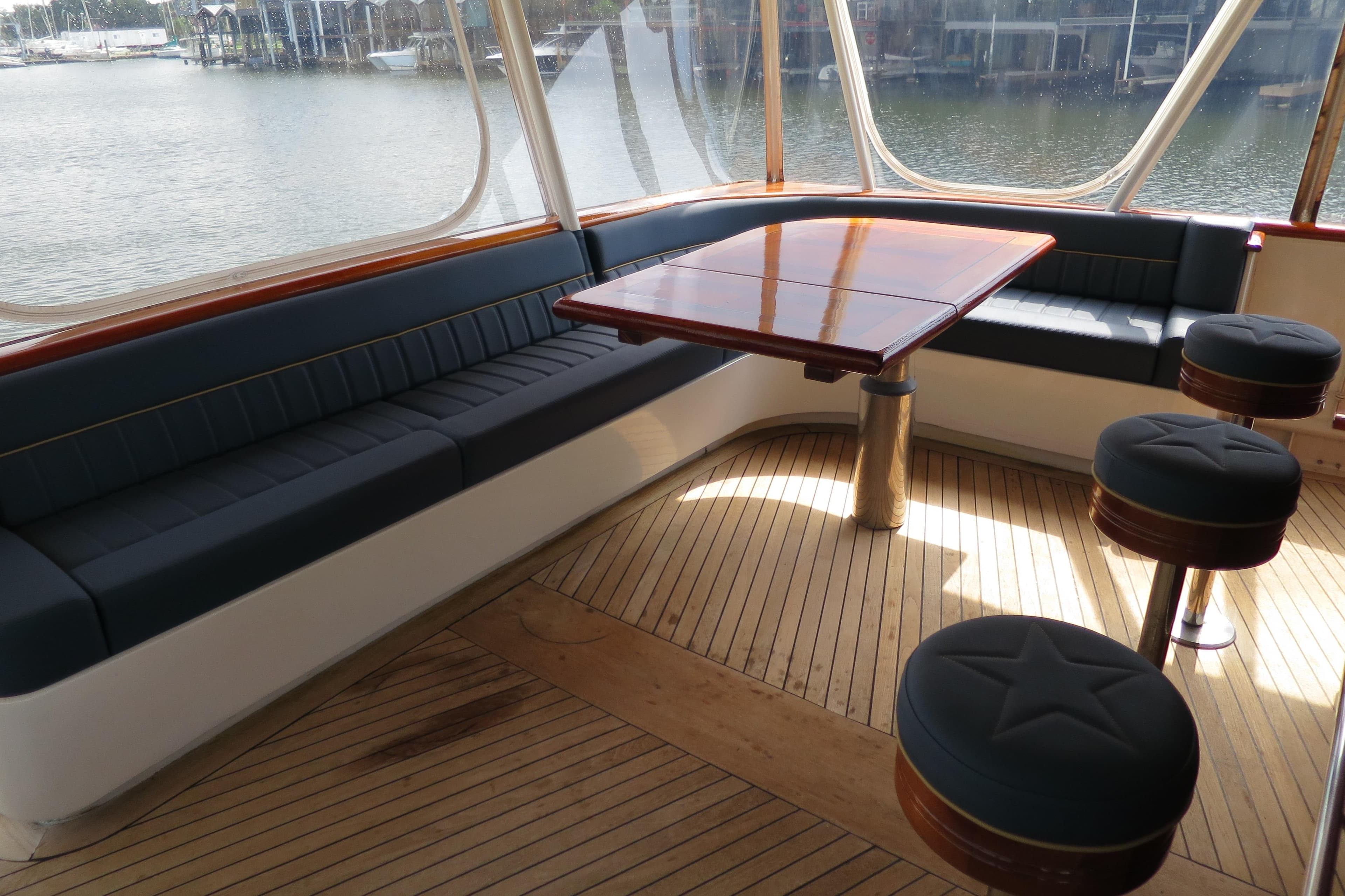 1964 Striker Cockpit interior with wooden flooring, cushioned seating, and waterfront view.