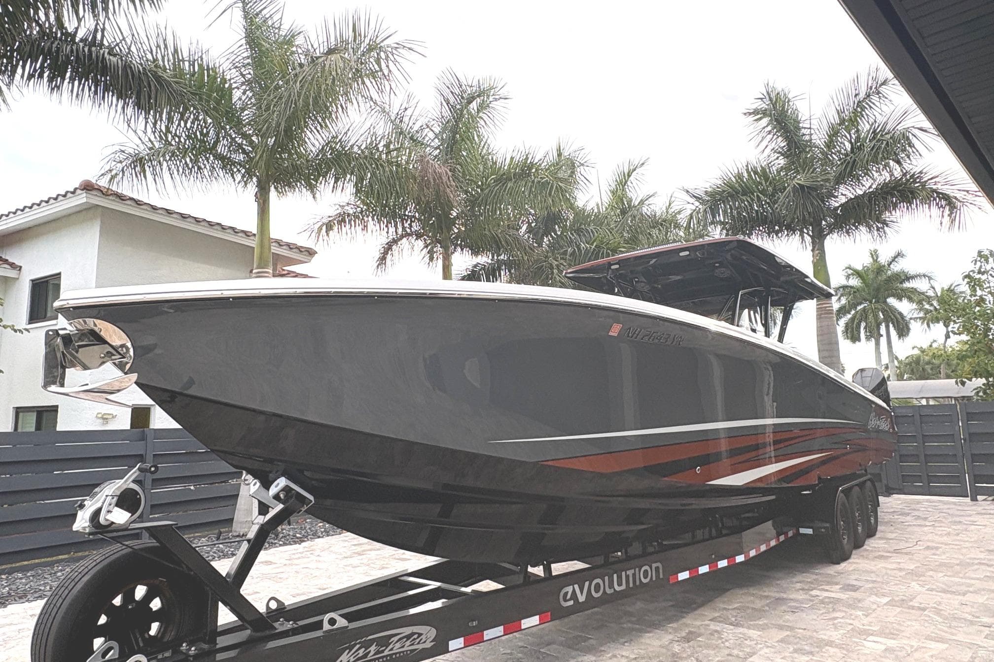 2024 Nor-Tech 390 Sport Center Console boat on trailer, surrounded by palm trees.
