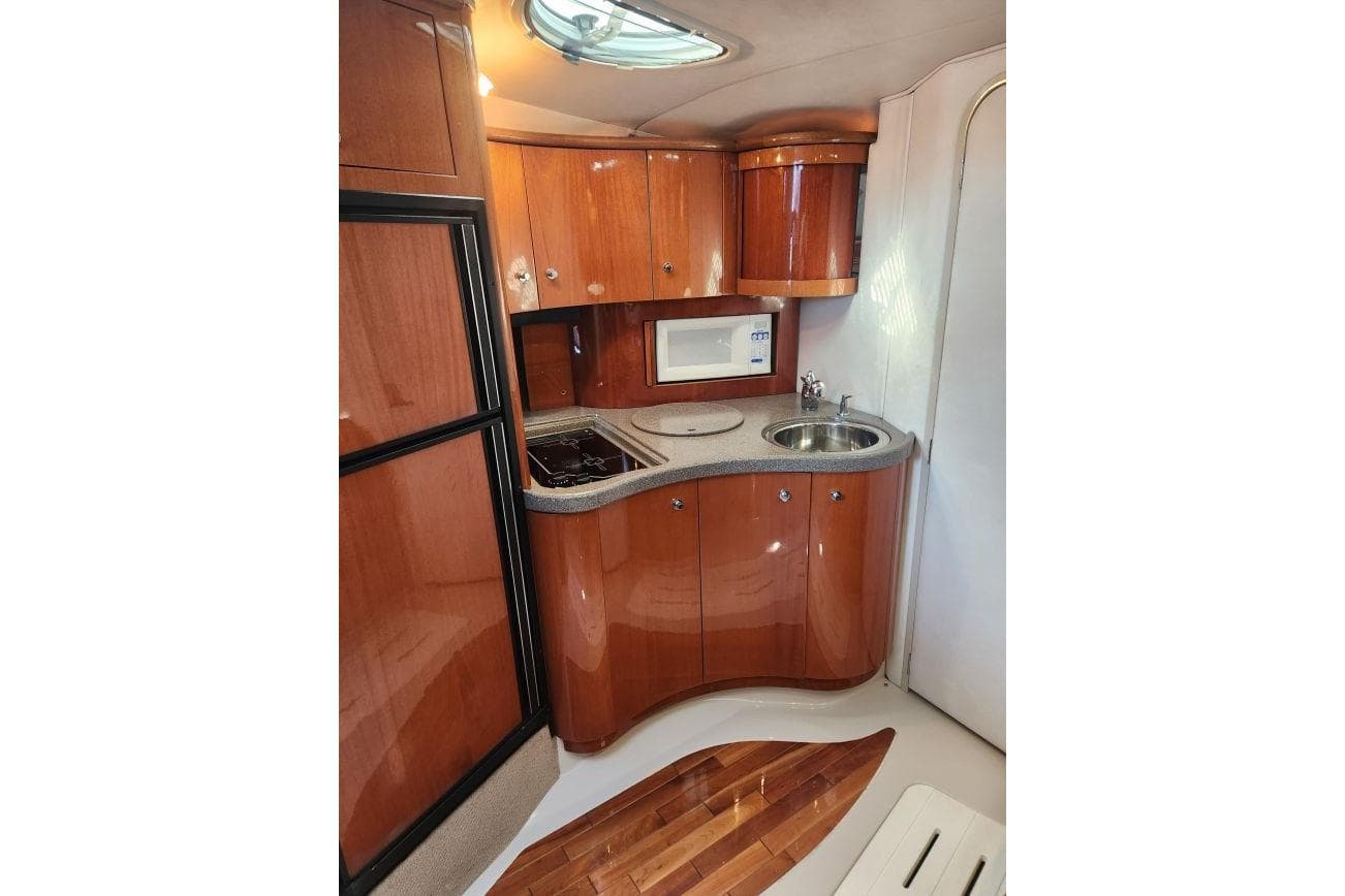 1999 Doral 360 SE Sunbridge yacht interior with wooden cabinets, sink, and compact kitchen area.