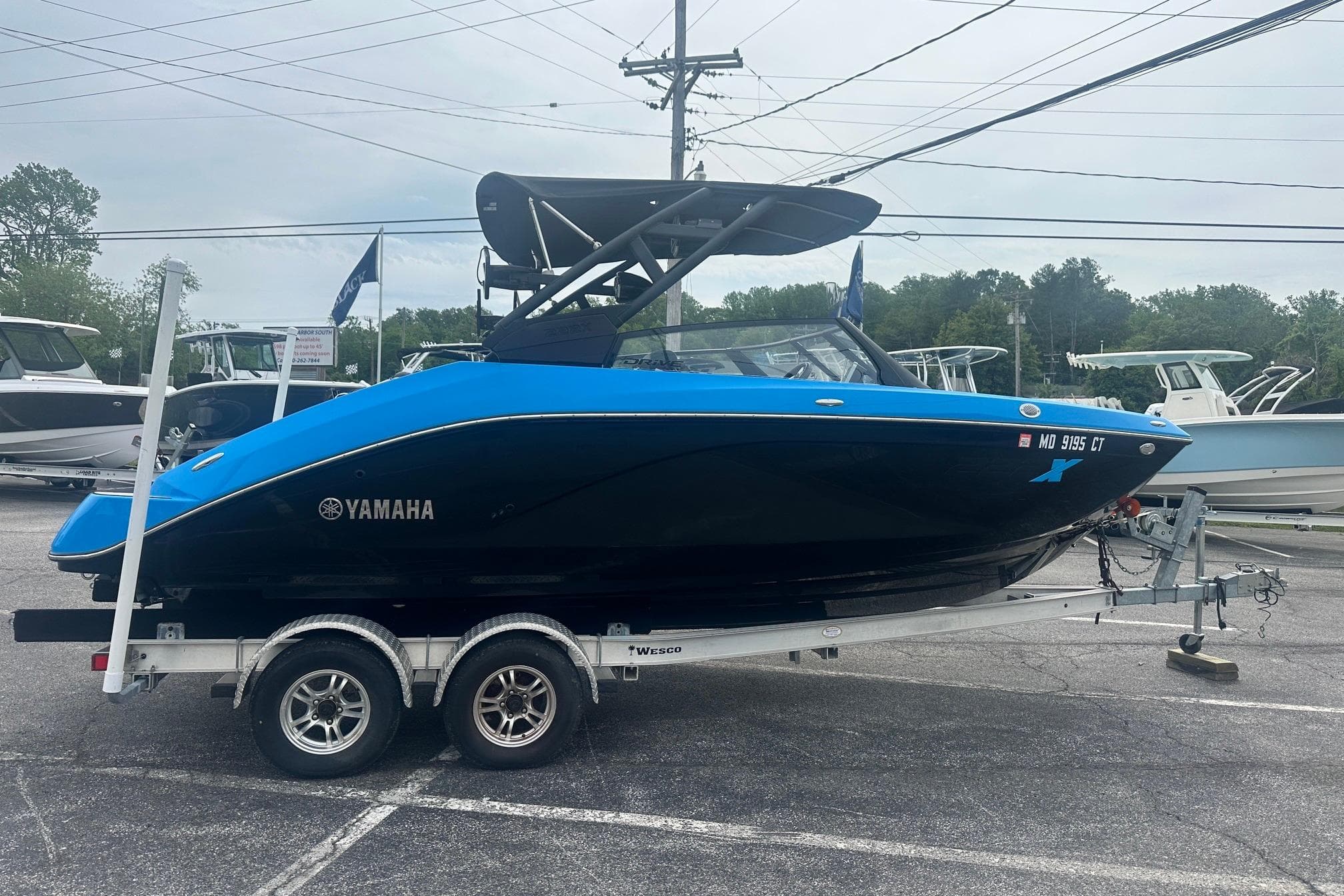 2023 Yamaha Boats 222XD in blue and black on a trailer, parked outdoors.