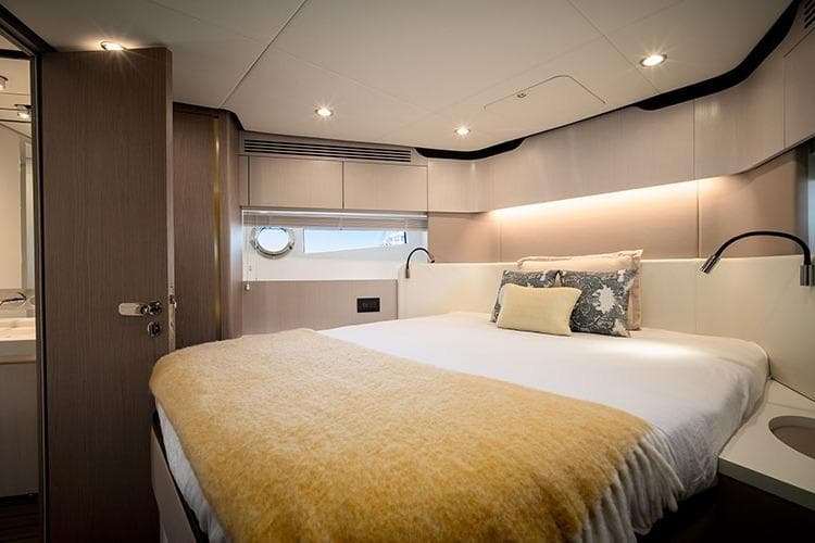 Luxurious bedroom interior of 2020 Azimut Fly 60 yacht with modern design and cozy bedding.