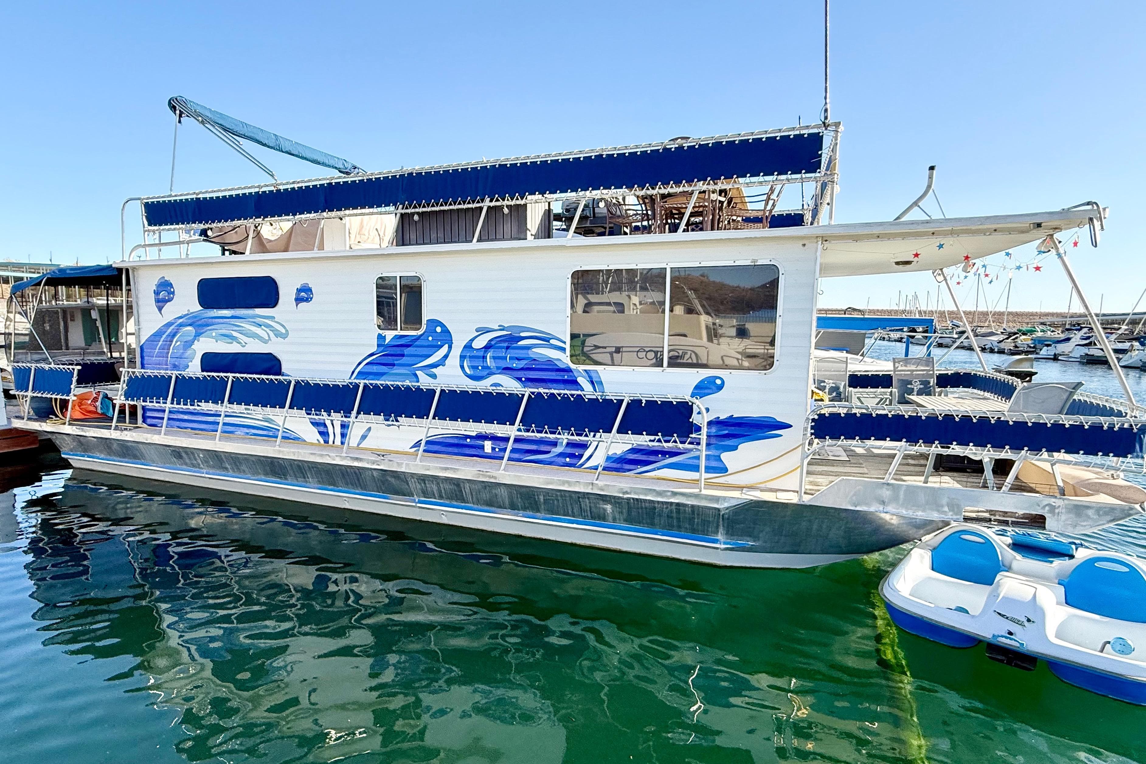 1986 Hilburn 4014 Executive houseboat with blue wave design docked in marina.