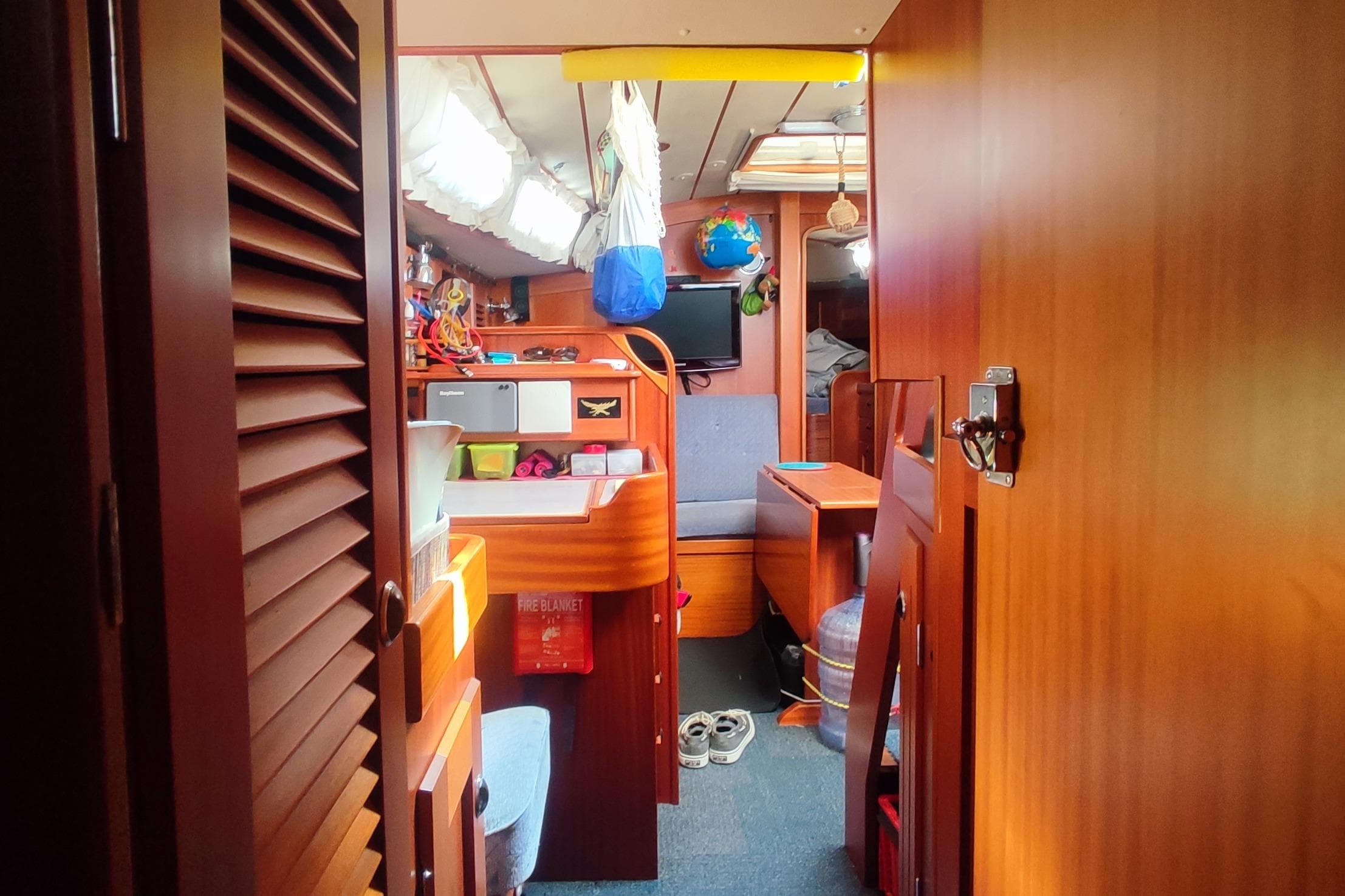 Interior of 2002 Hallberg-Rassy 36 MKII sailboat, featuring cozy wooden furnishings and organized storage.