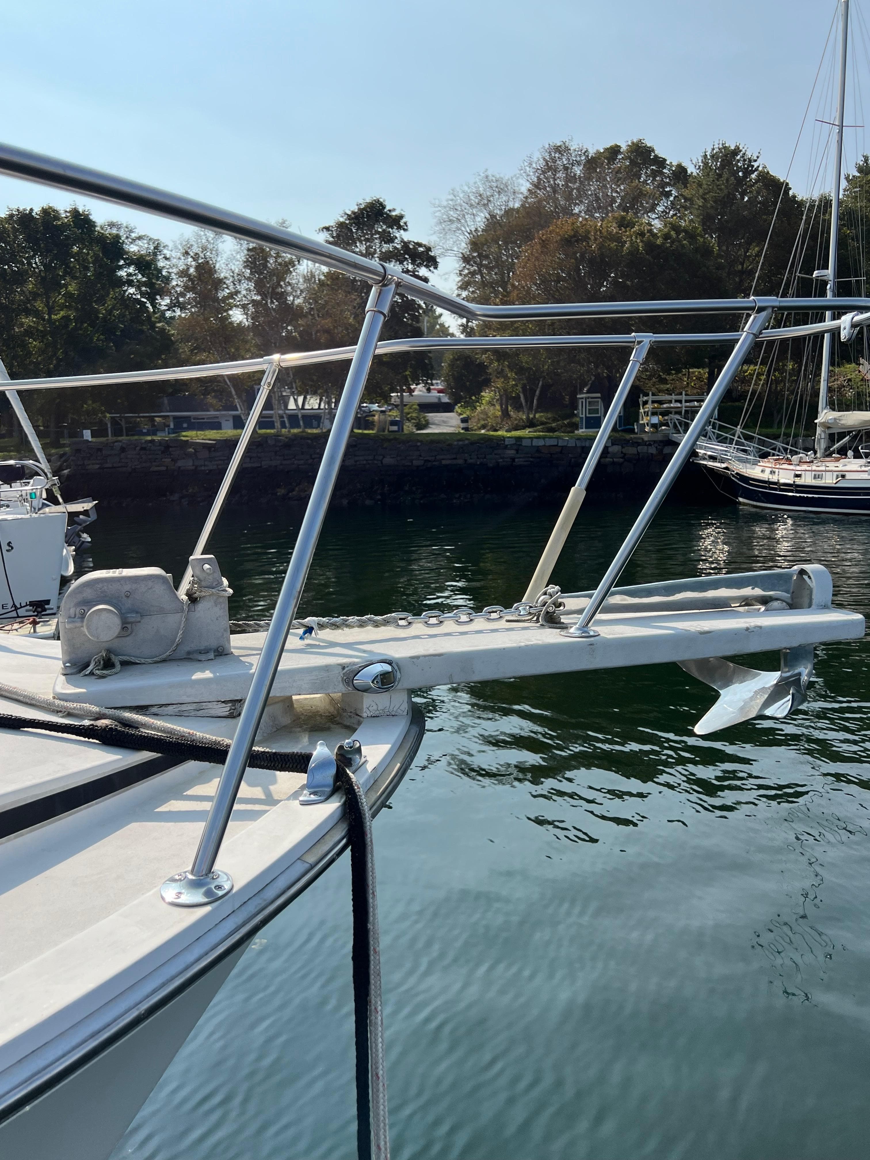 1987 Bertram Flybridge Cruiser anchored by a serene waterfront with trees in the background.