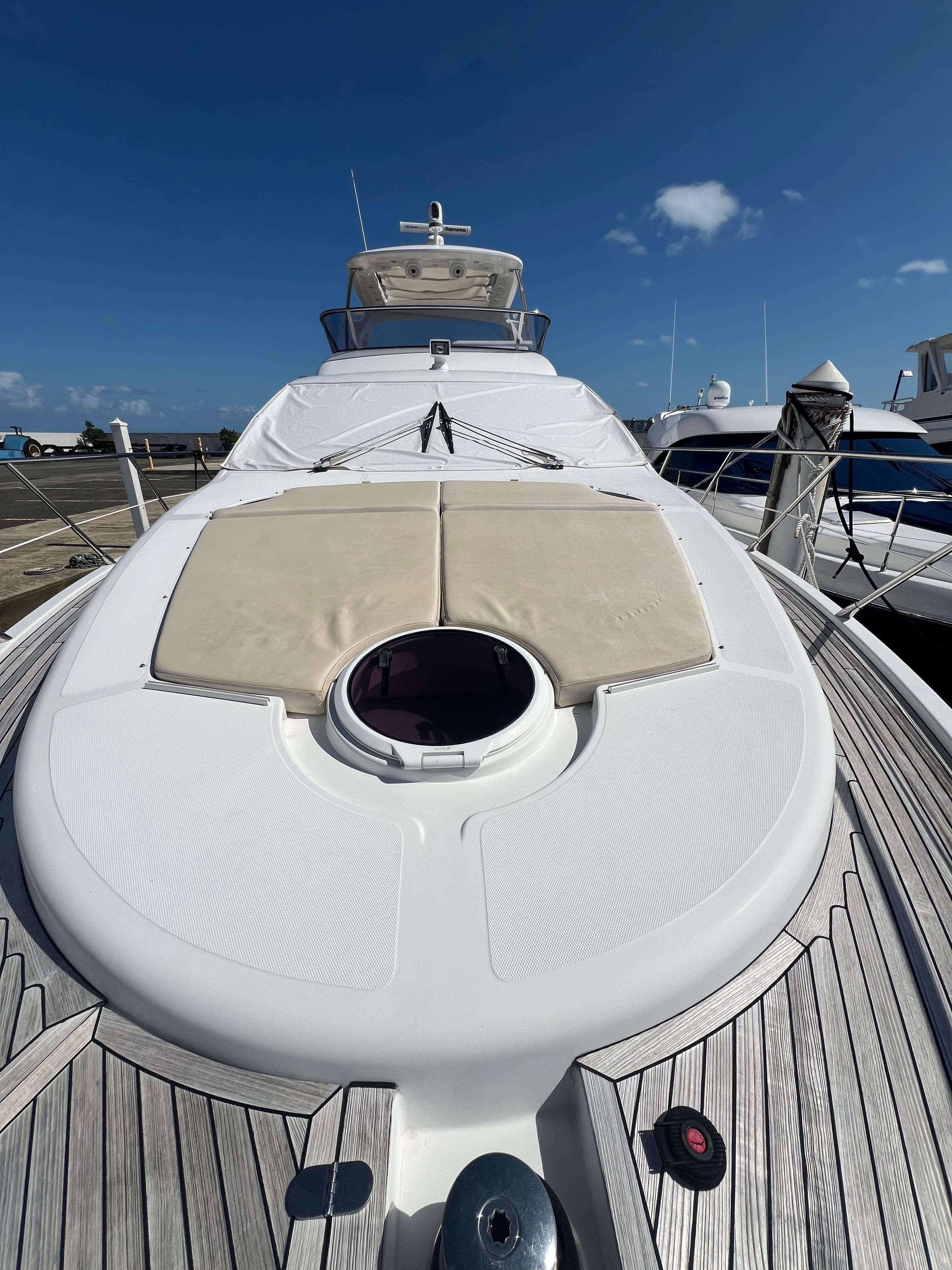2016 Azimut 54fly yacht with sunbathing deck, docked under clear blue sky.