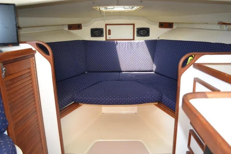 1988 Blackfin 29 Flybridge cabin interior with blue cushioned seating and wooden accents.